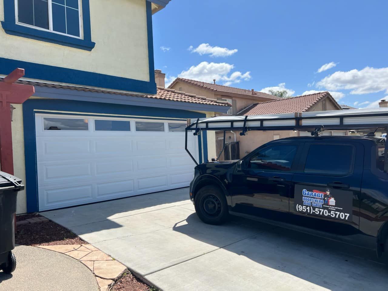 A black truck is parked in front of a white garage door.