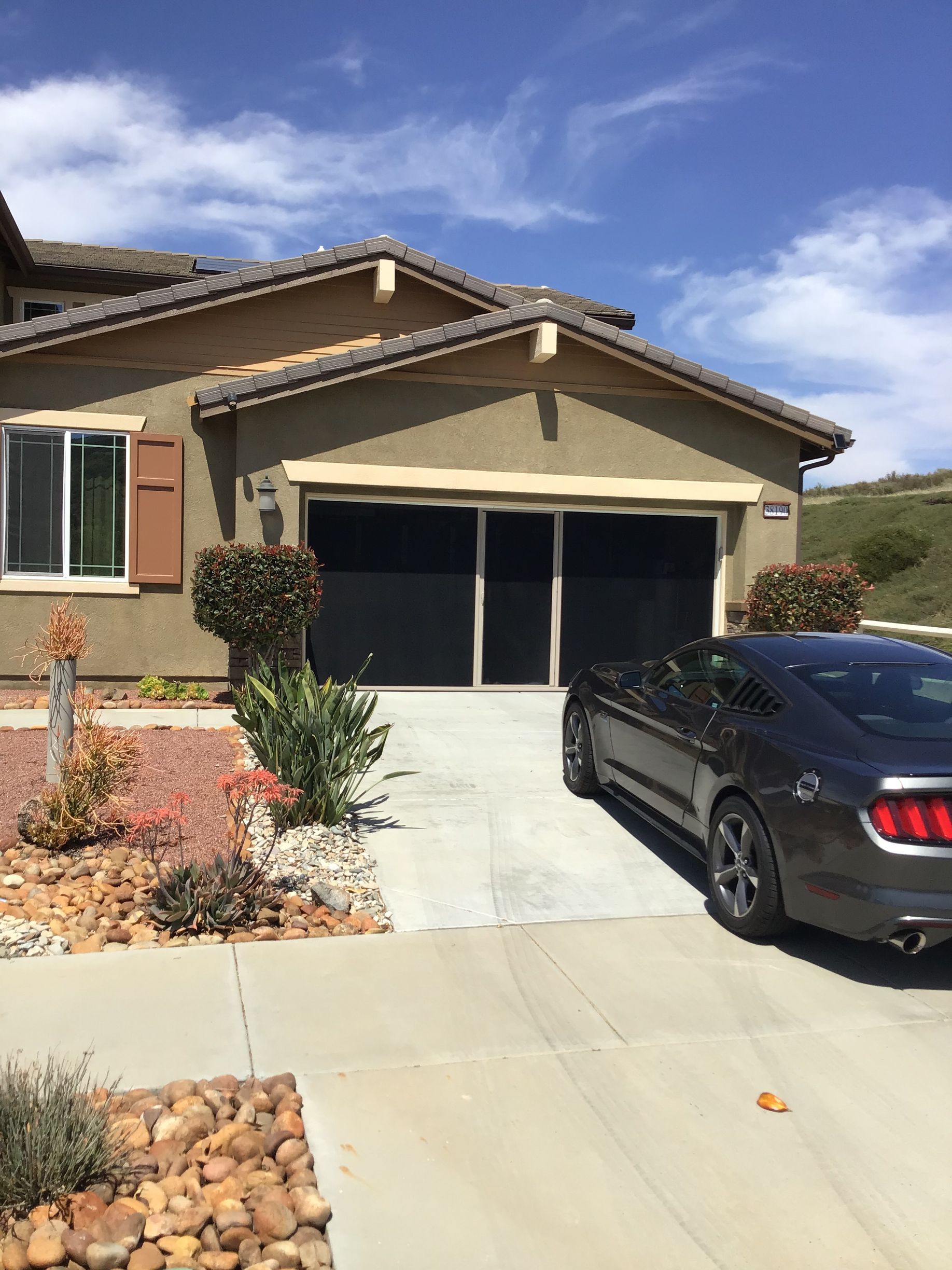 A car is parked in front of a house on a sunny day.