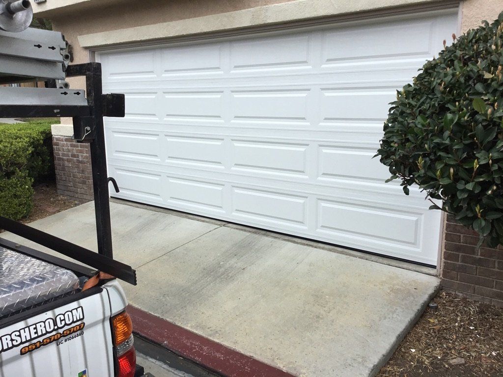 A white truck is parked in front of a white garage door.