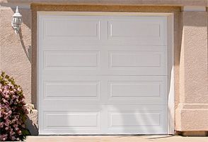 A white garage door is sitting on the side of a house.
