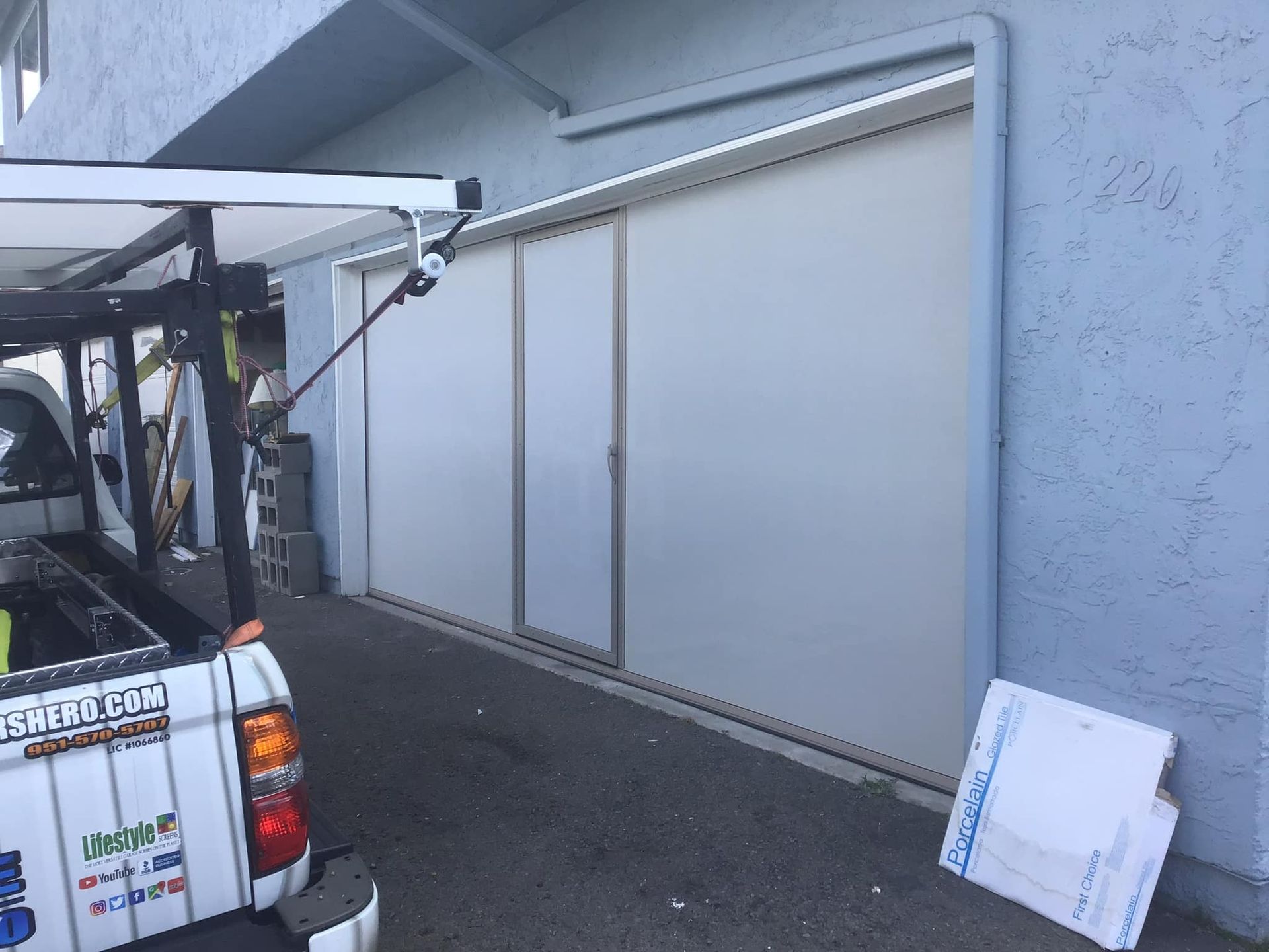 A white truck is parked in front of a garage door.
