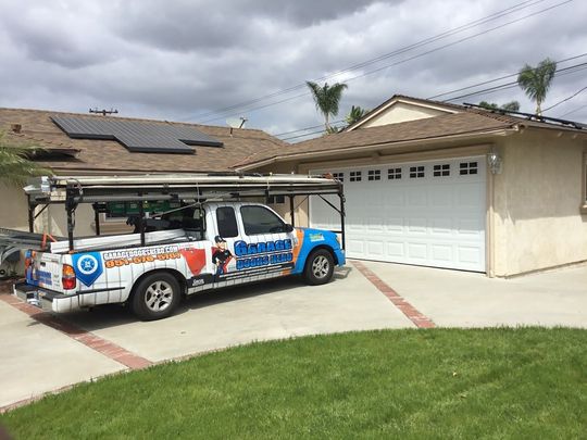 A truck is parked in front of a house with solar panels on the roof.