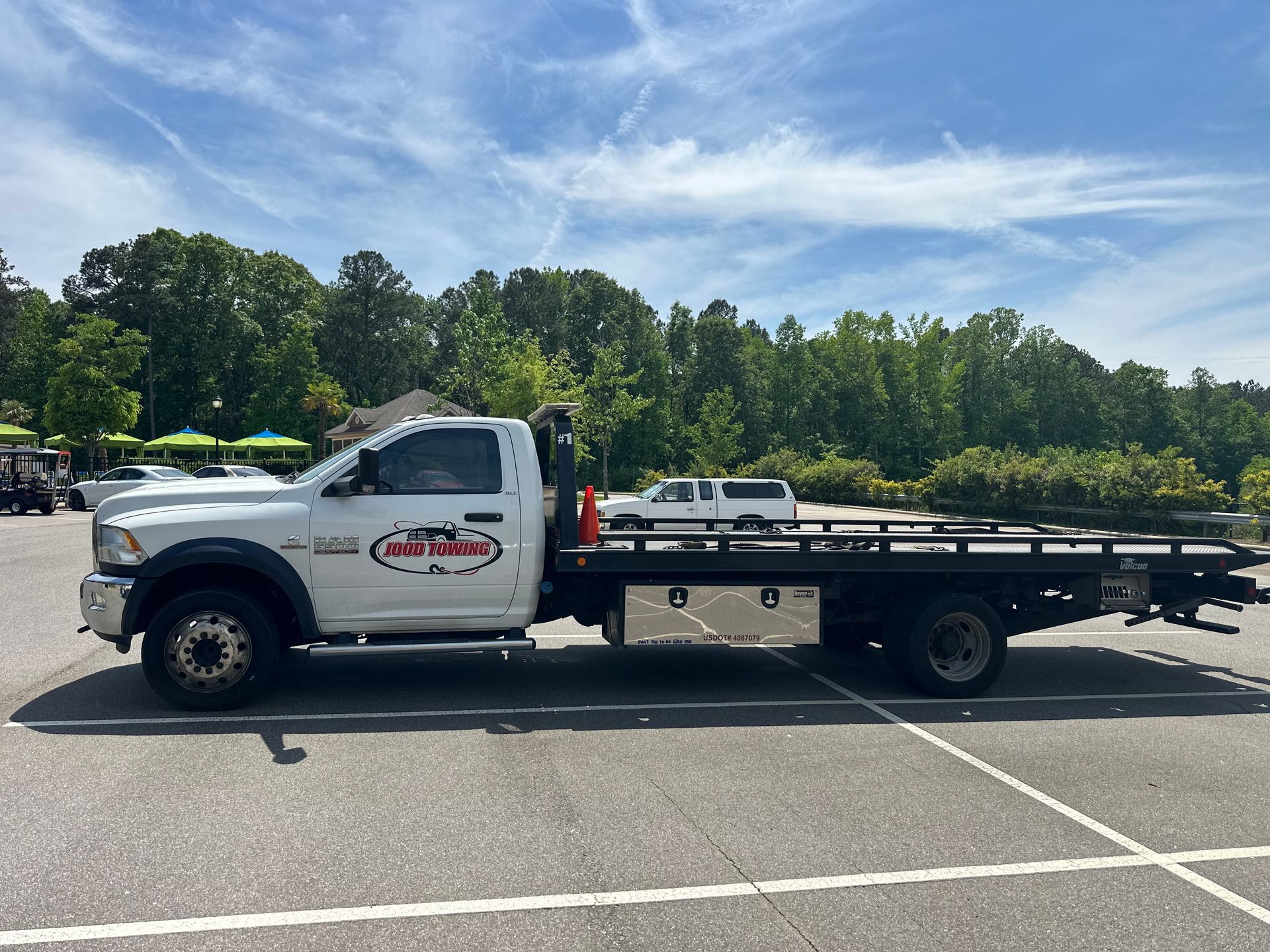 A white tow truck is parked in a parking lot.
