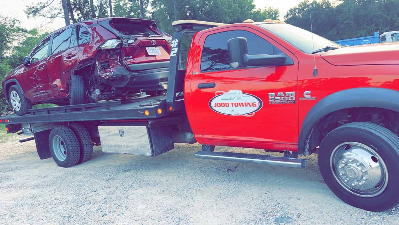 A red tow truck with a car on the back of it.
