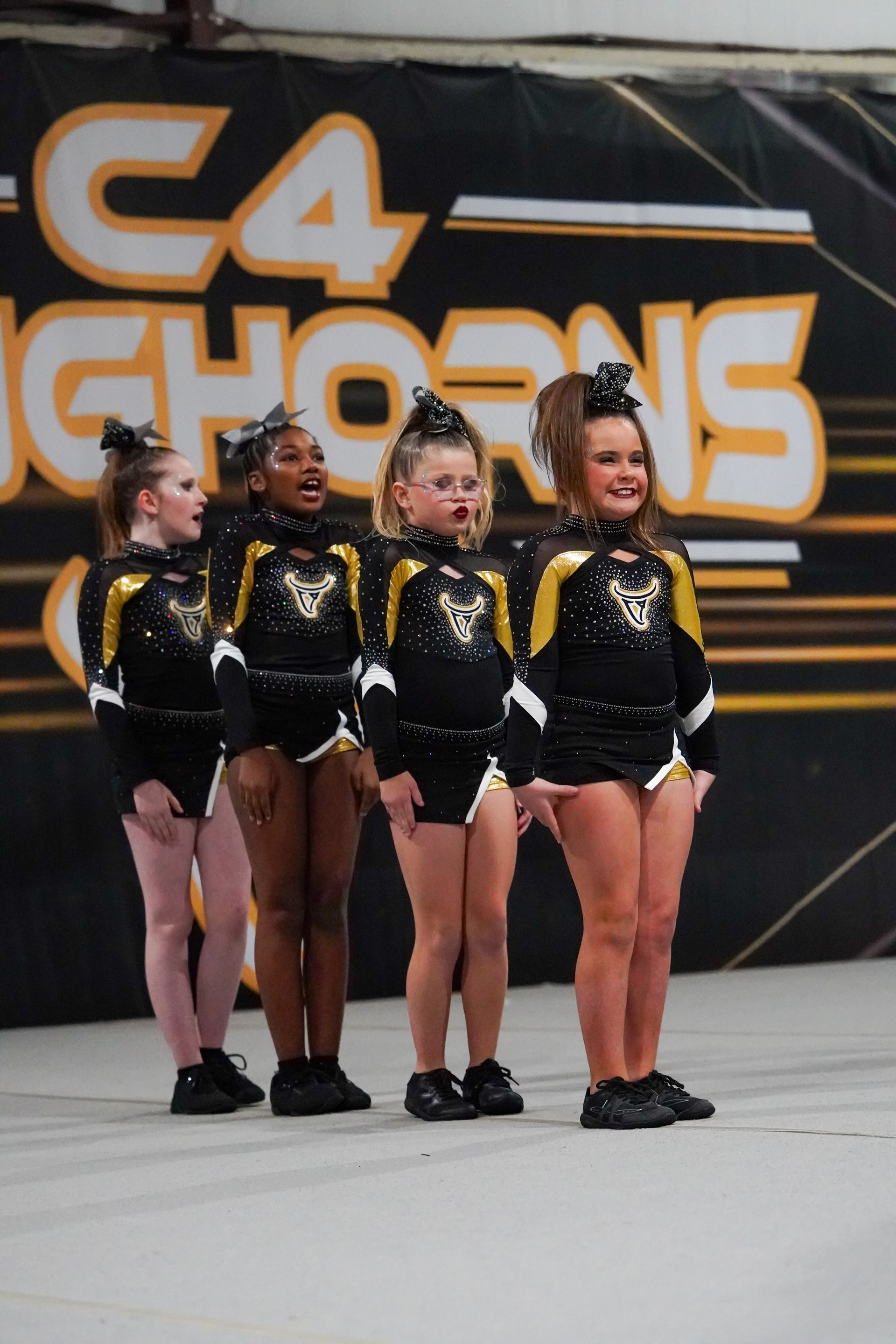 Cheerleaders in black and gold uniforms performing on a stage.