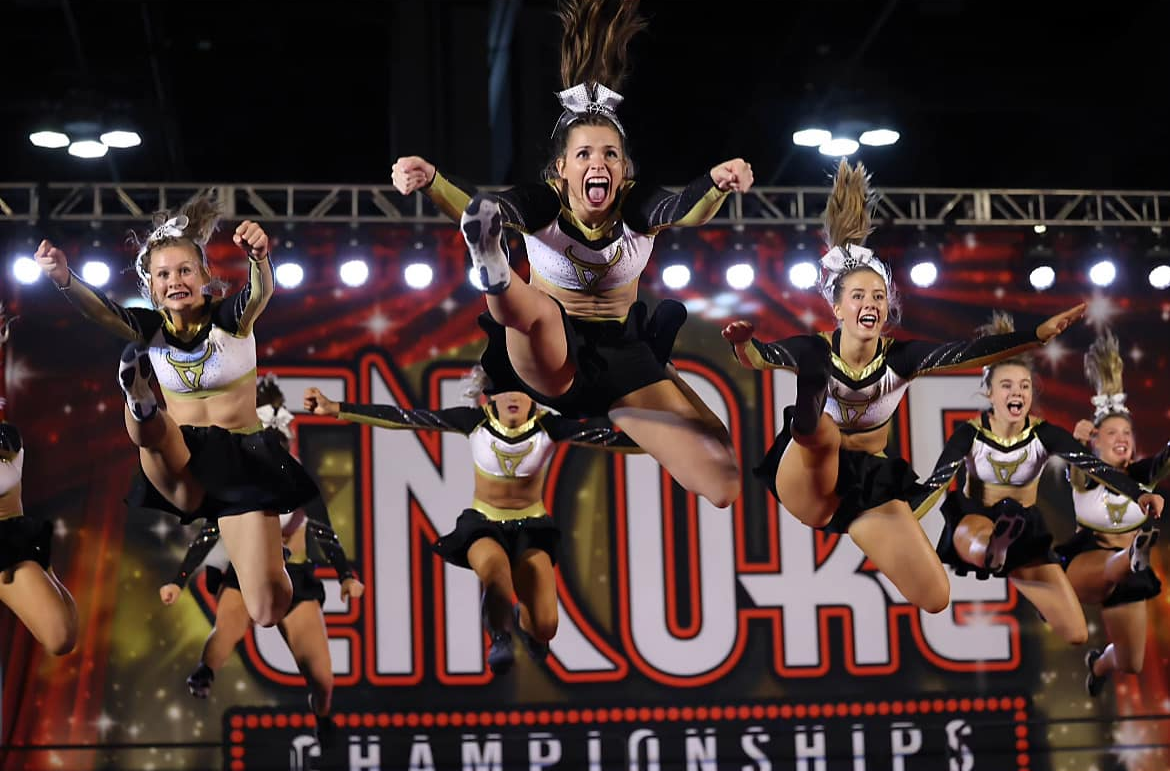 Cheerleaders jumping mid-air at a competition. 