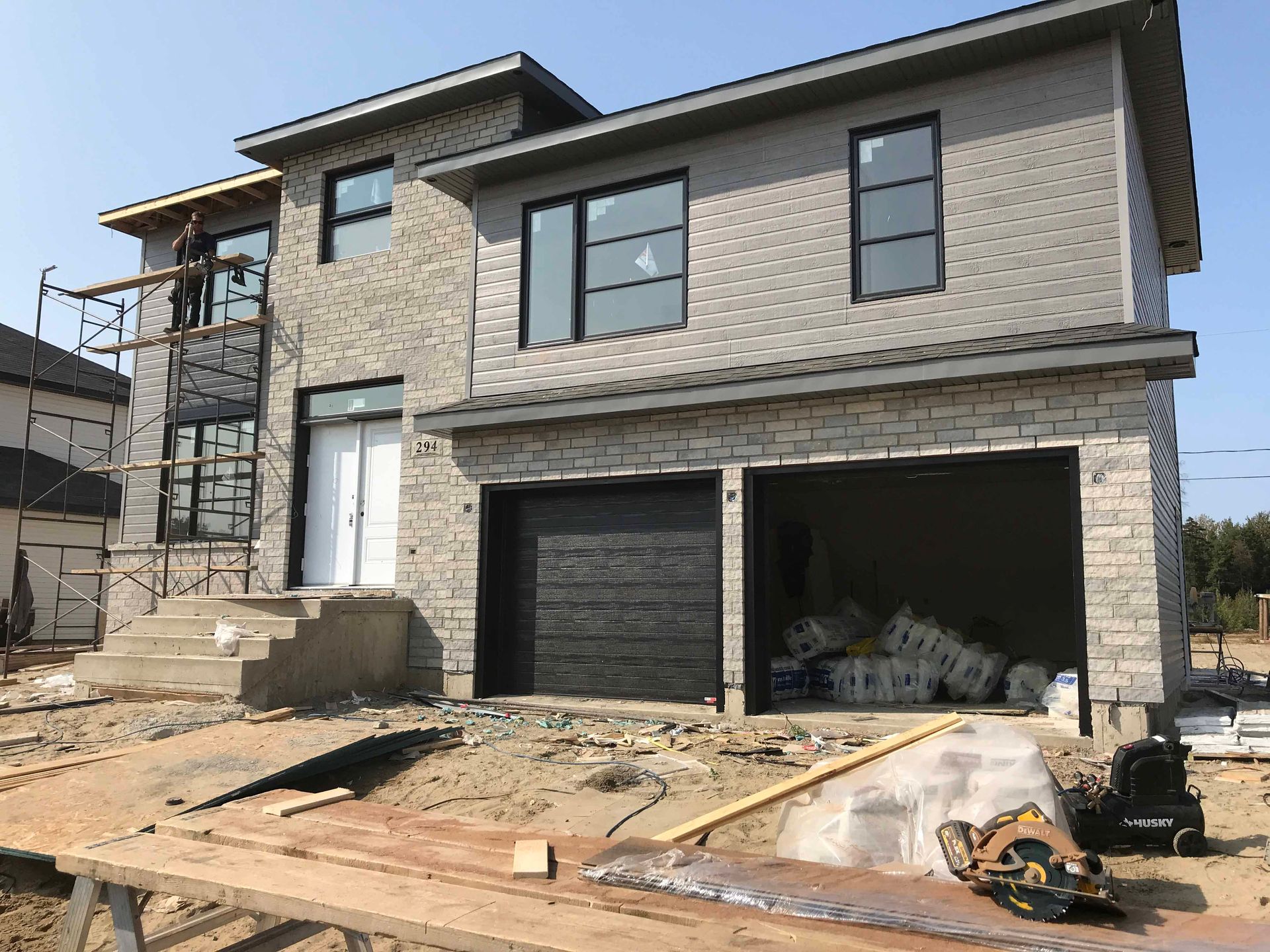 Une grande maison en briques est en construction avec un garage et des escaliers.