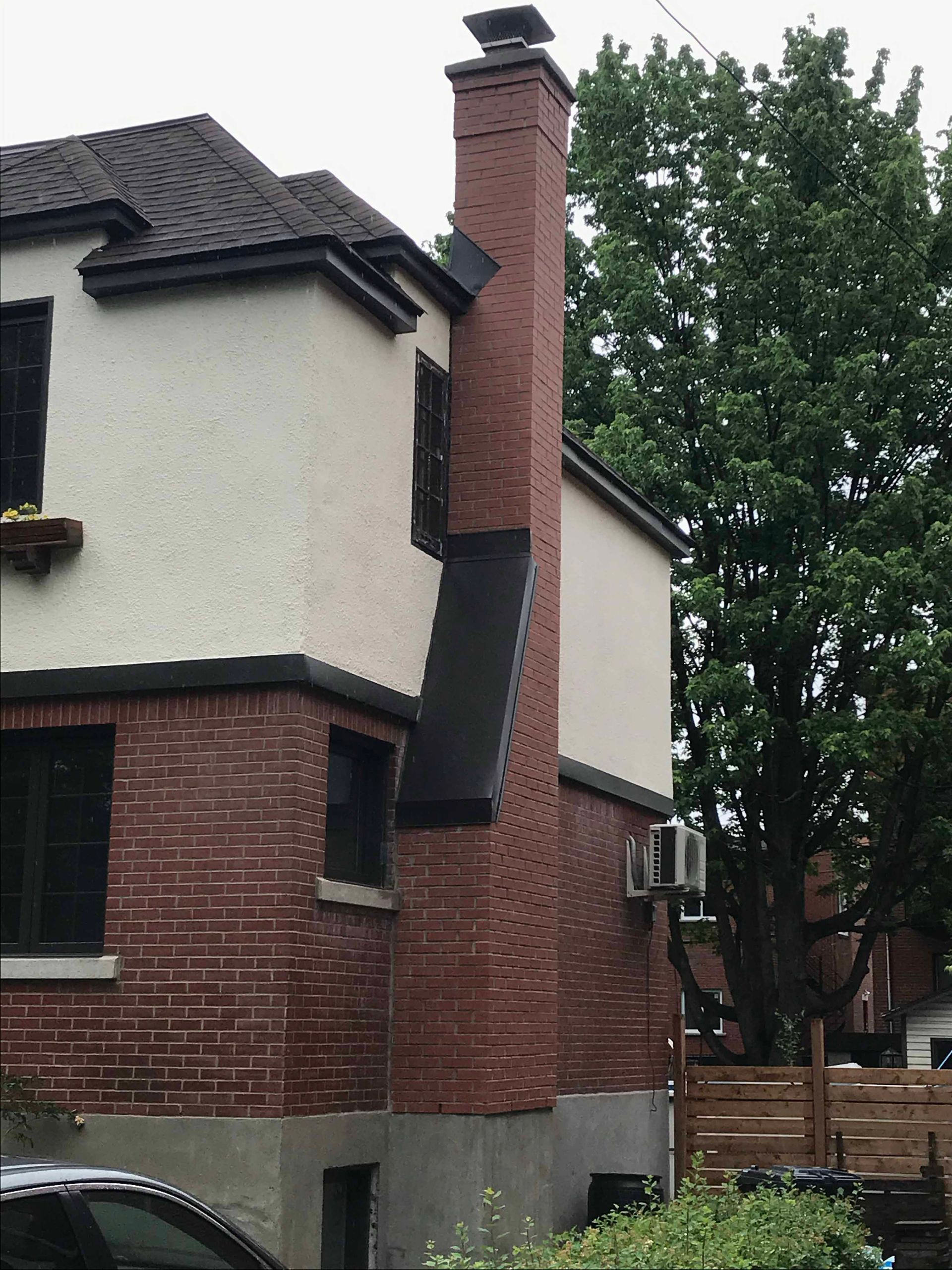 Une maison blanche avec une cheminée en briques sur le côté