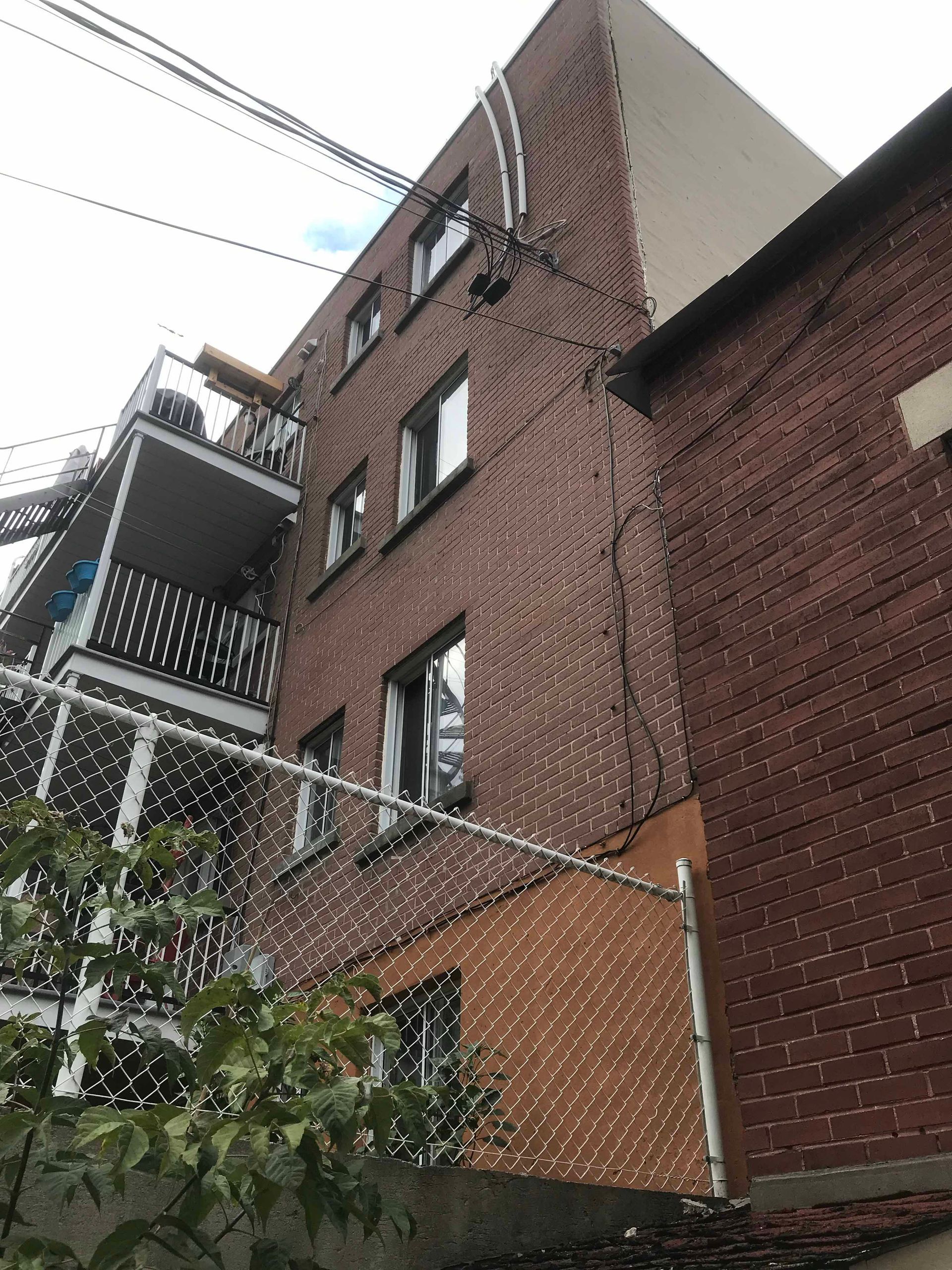 Un bâtiment en briques avec un balcon et une clôture devant.