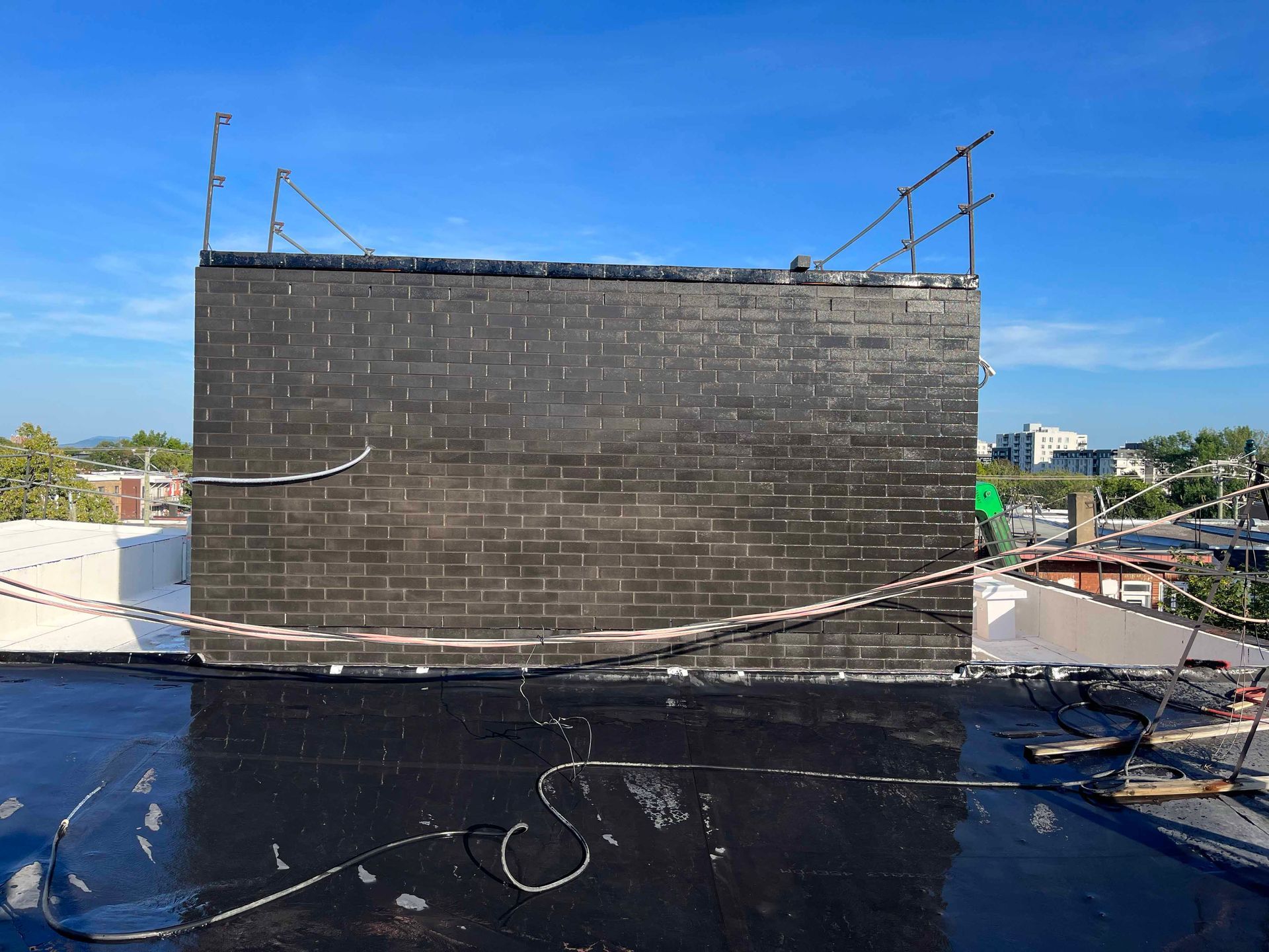 Un grand mur de briques noires repose sur un toit.