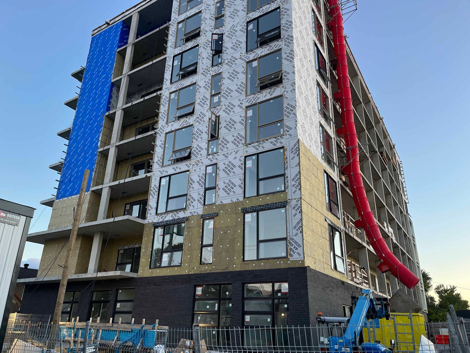 Un grand bâtiment en construction avec un tuyau rouge qui en sort.