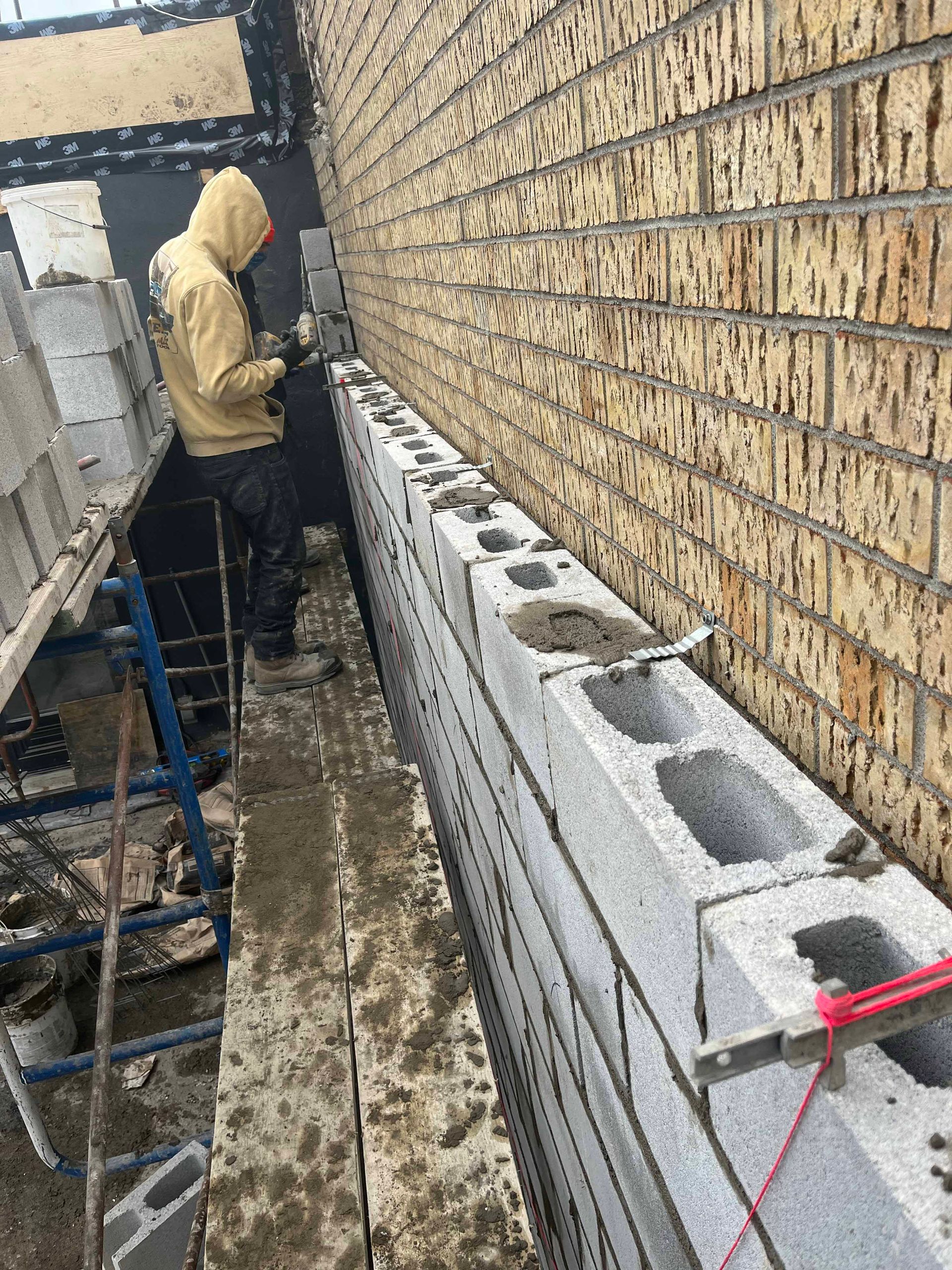 Un homme travaille sur un mur de briques avec des blocs de béton.