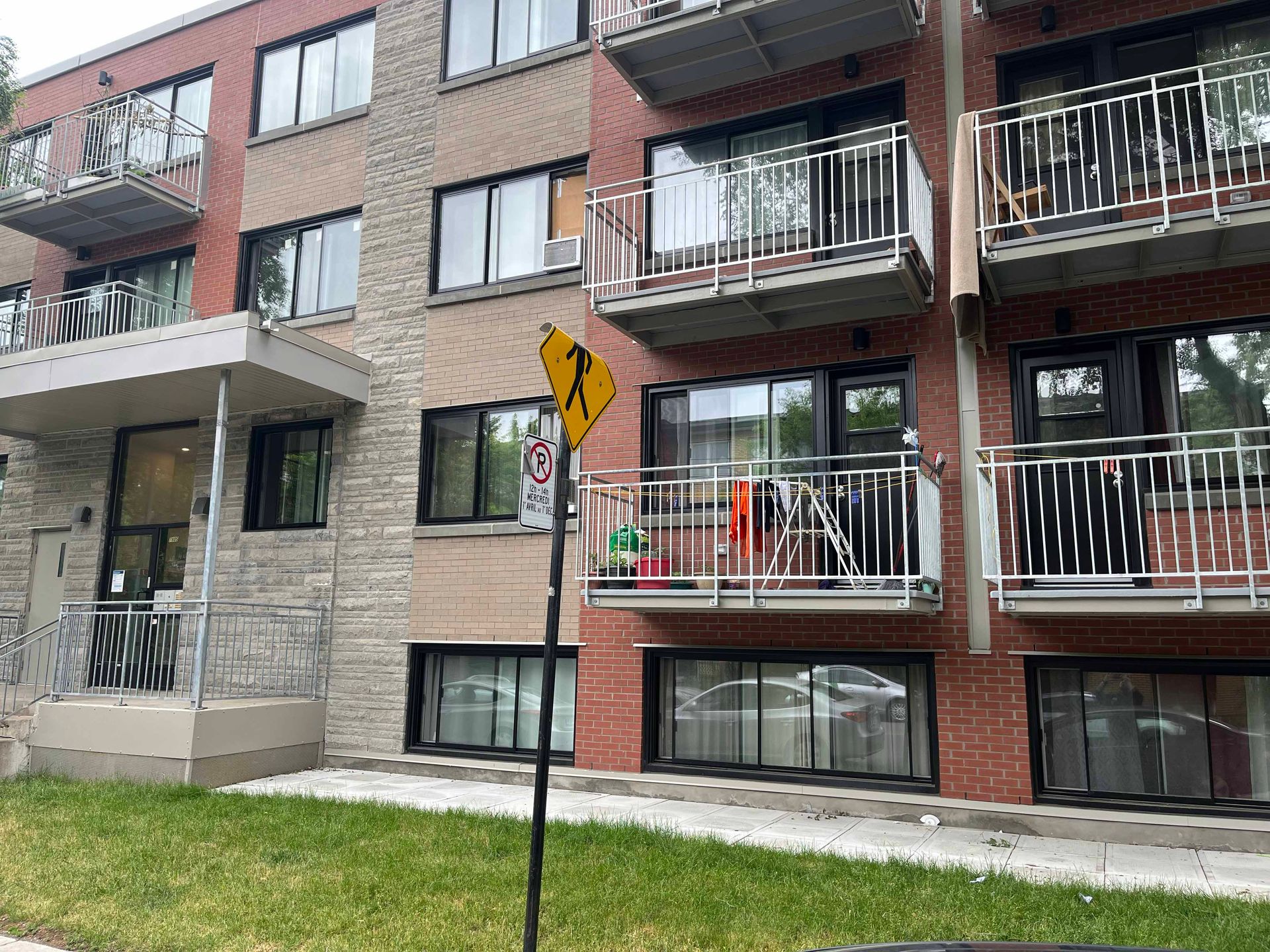 Un grand immeuble d'appartements avec un panneau jaune devant.