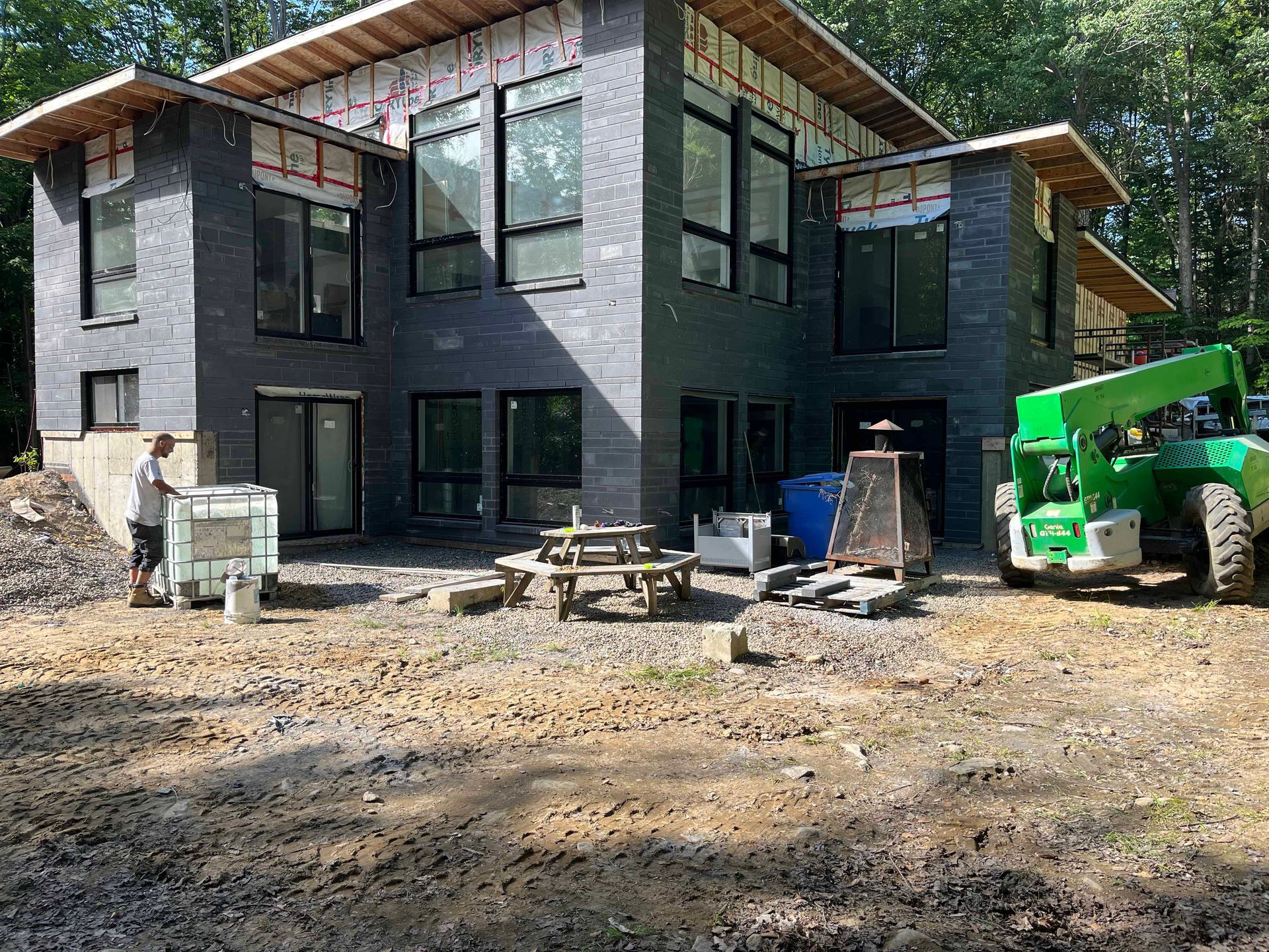 Un homme se tient devant une grande maison en construction.