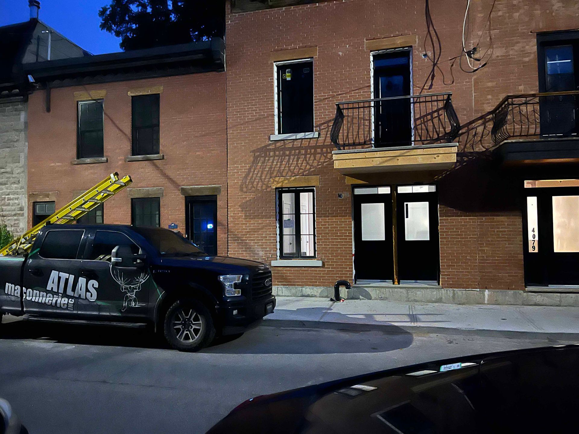 Un camion Atlas noir est garé devant un bâtiment en briques