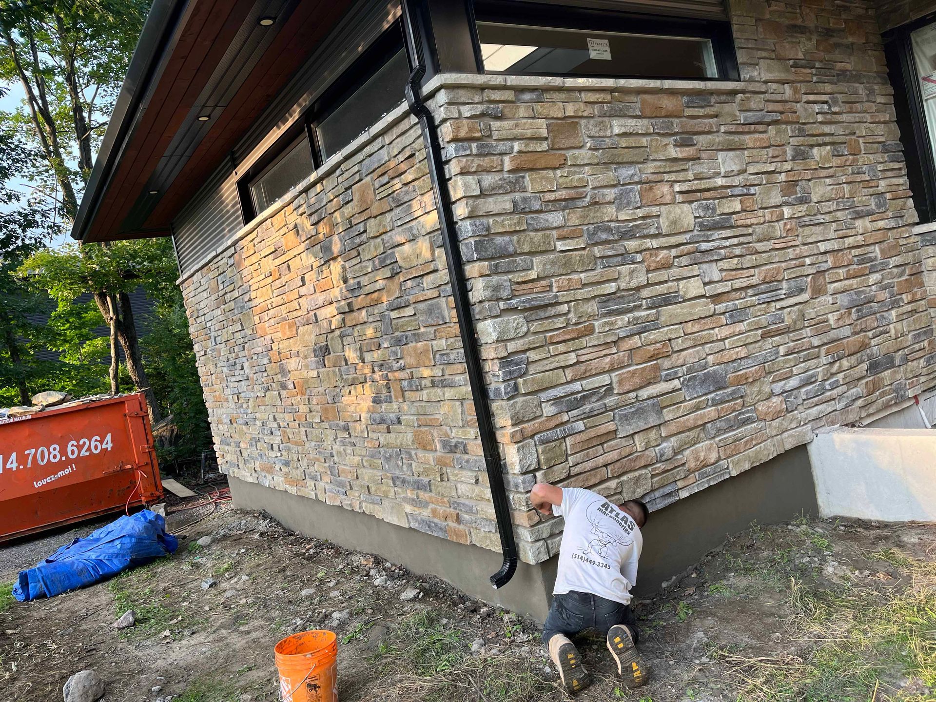 Un homme travaille sur le côté d'un bâtiment en briques.