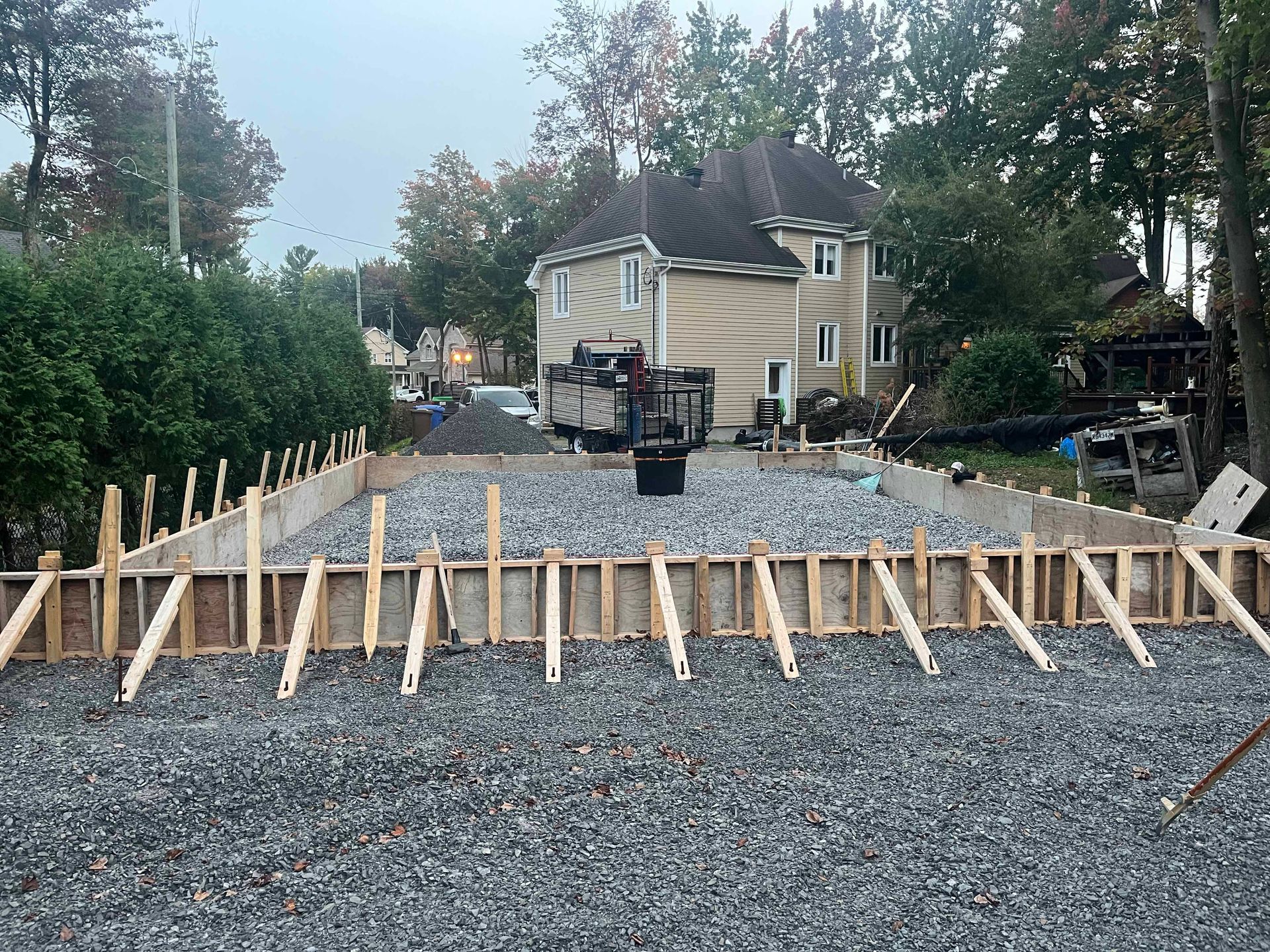 Une fondation en béton est en train d'être construite devant une maison.