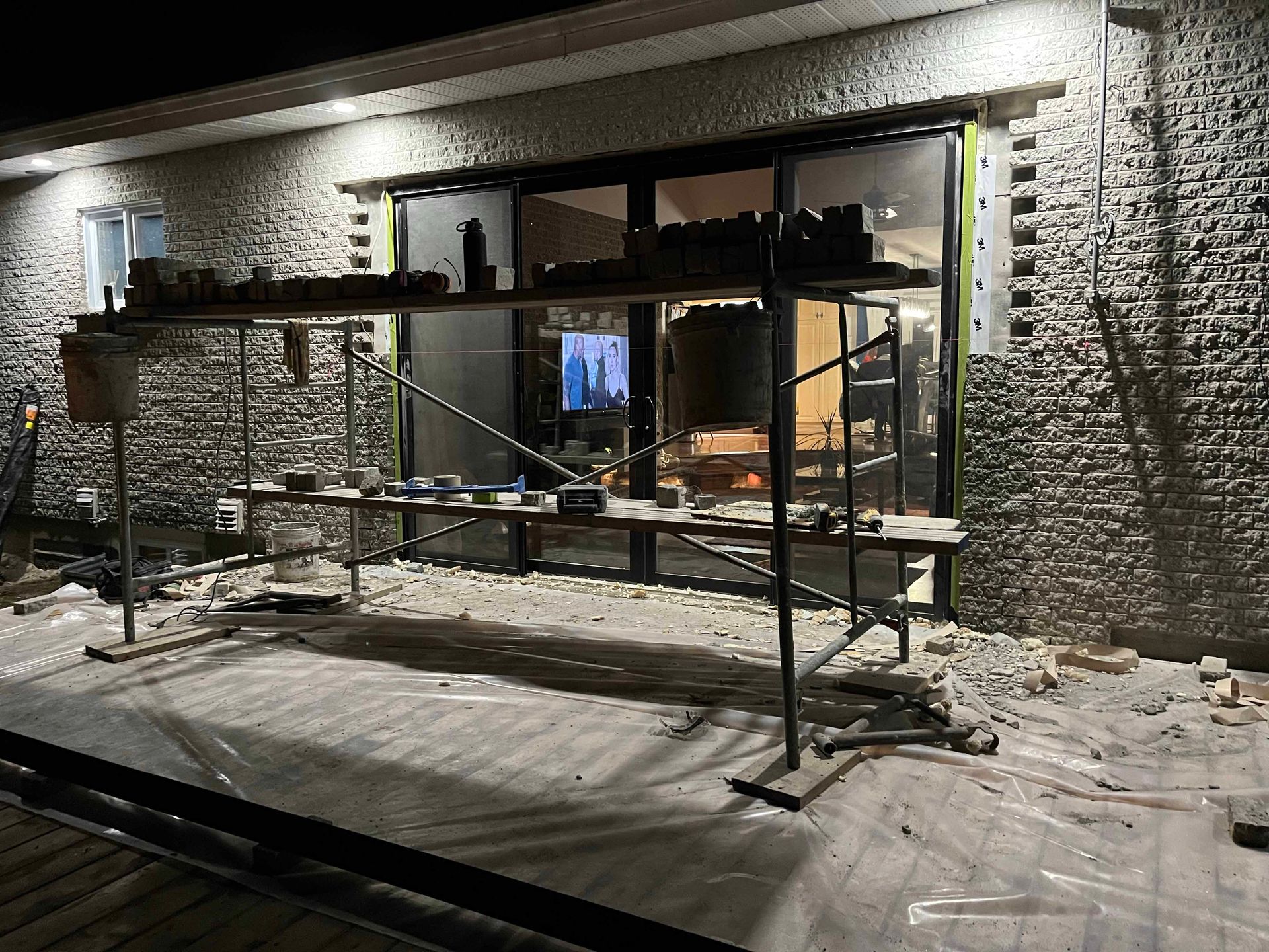 Un échafaudage est posé devant un bâtiment en briques la nuit.