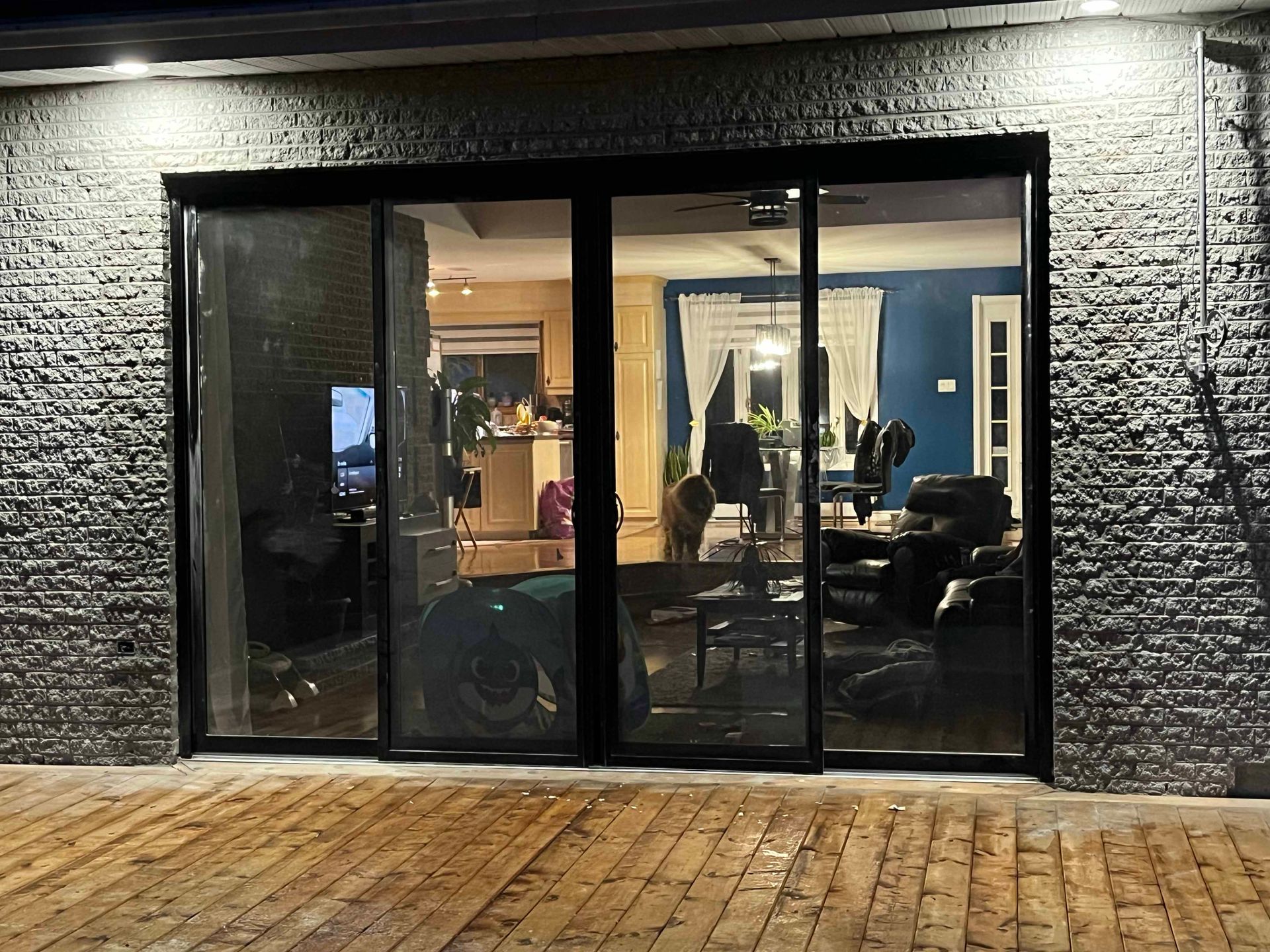 Un mur de briques avec une porte coulissante en verre menant à un salon