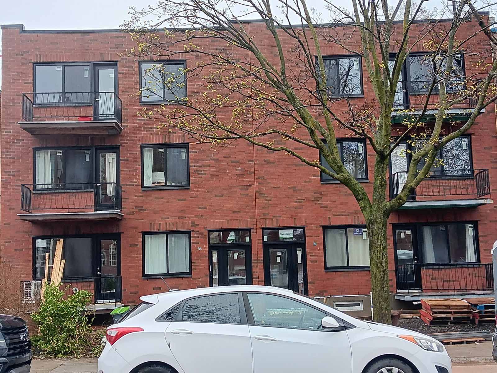 Une voiture blanche est garée devant un bâtiment en briques.