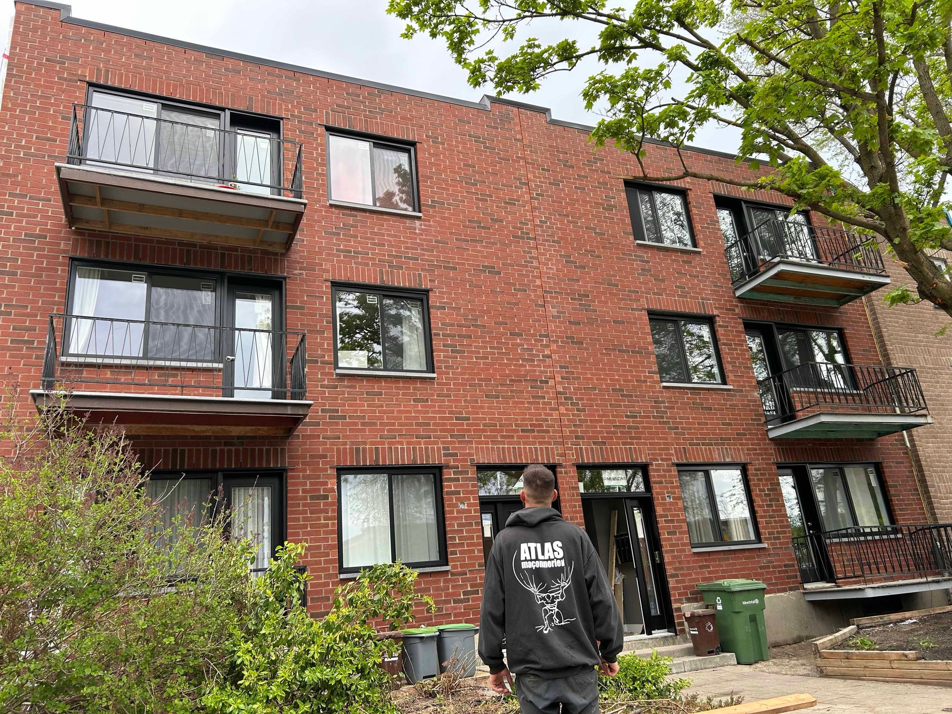 Un homme se tient devant un grand bâtiment en briques.