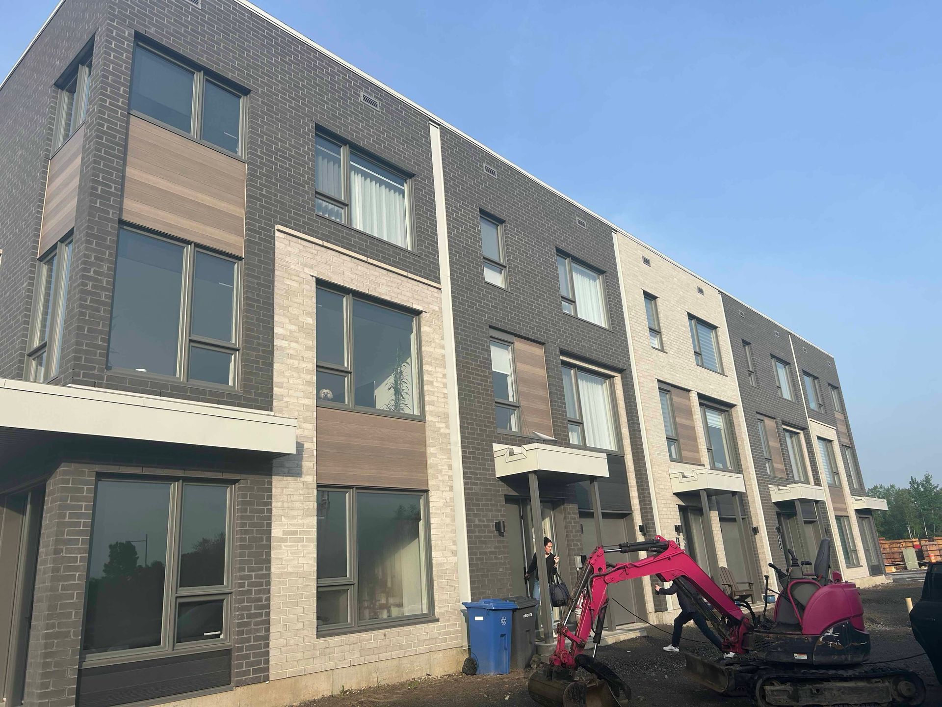 Un grand bâtiment en briques avec une excavatrice rouge garée devant.