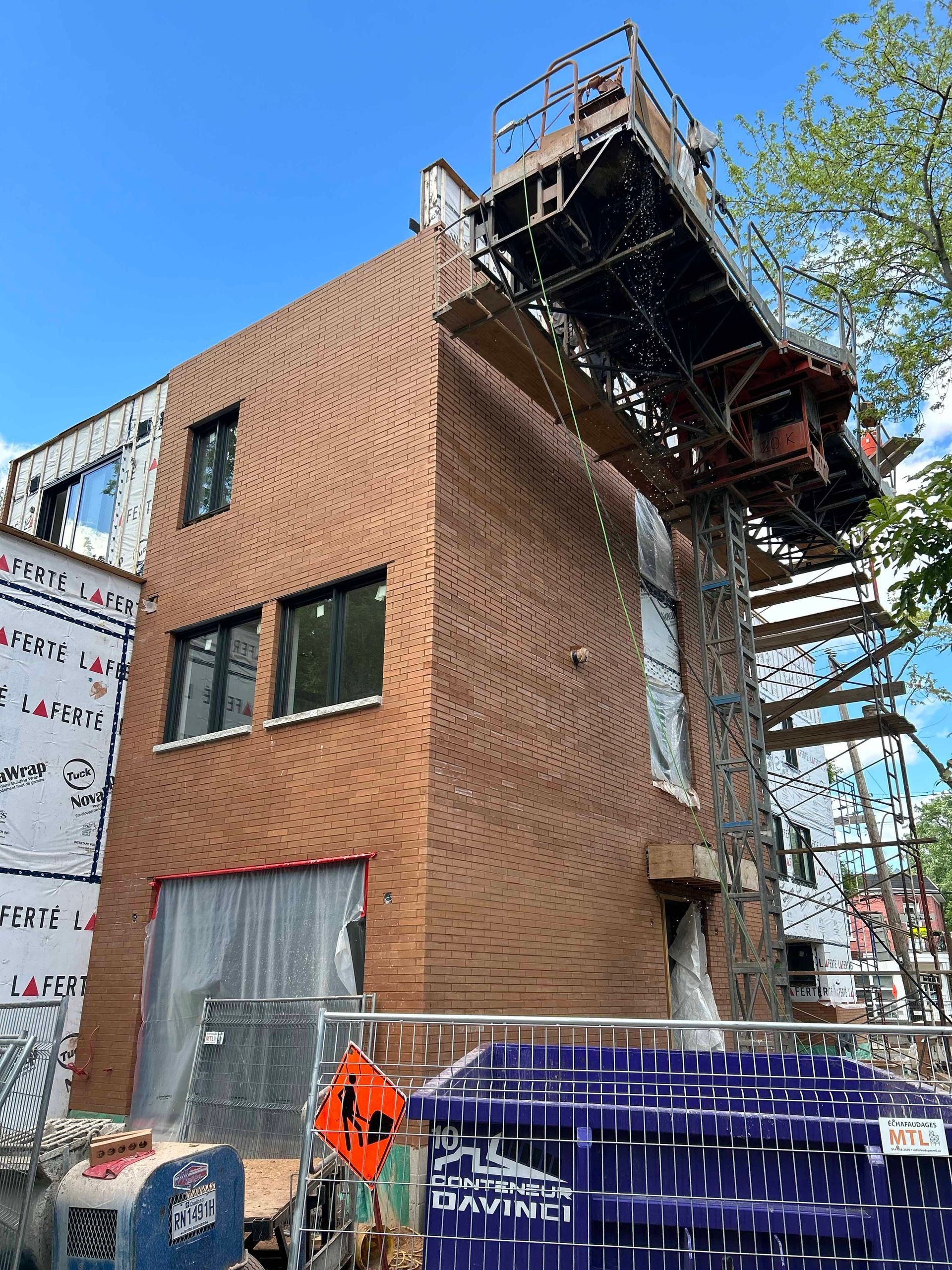 Un grand bâtiment en briques en construction avec une grue au sommet.