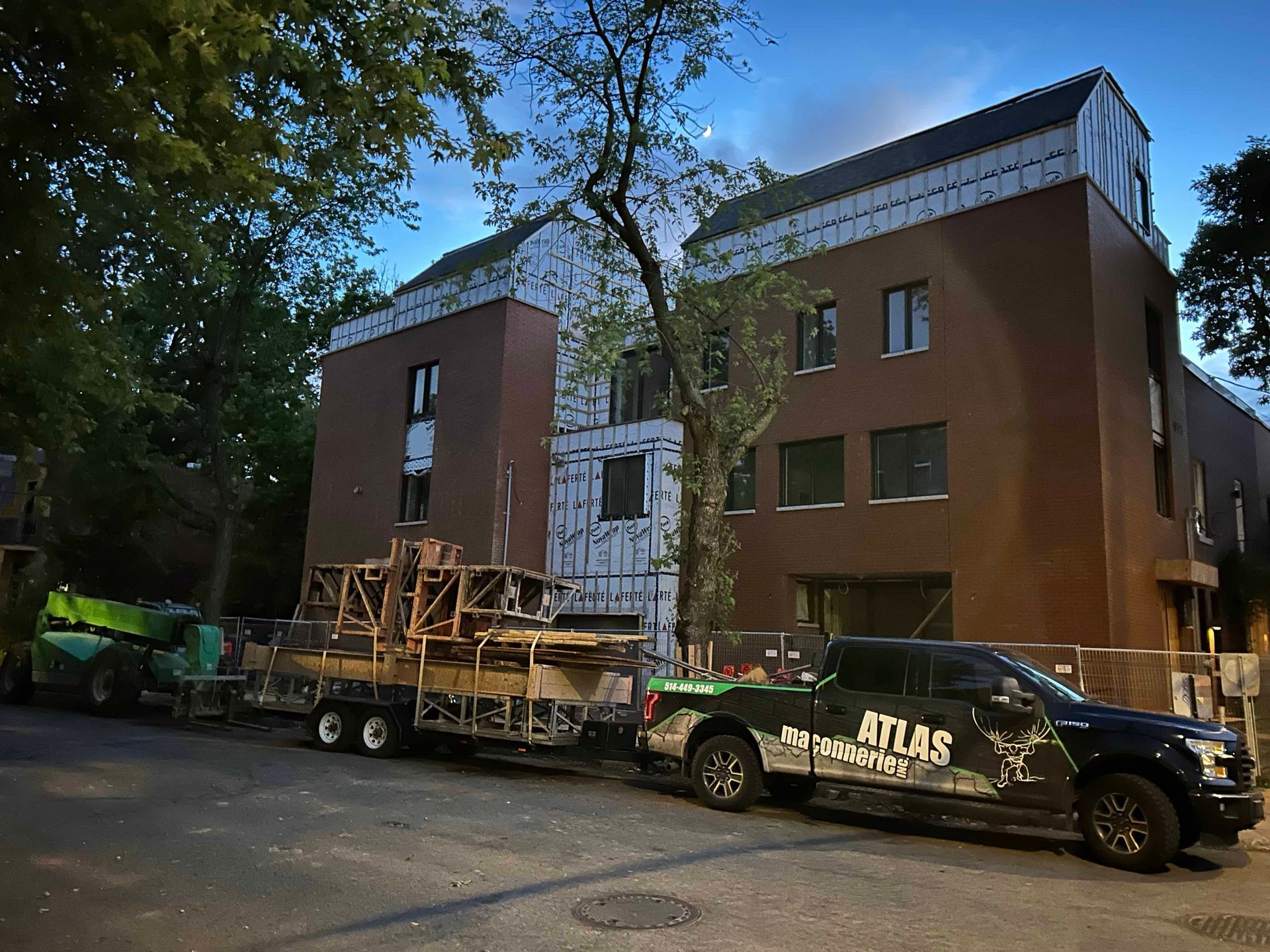 Un camion atlas noir est garé devant un bâtiment en construction.