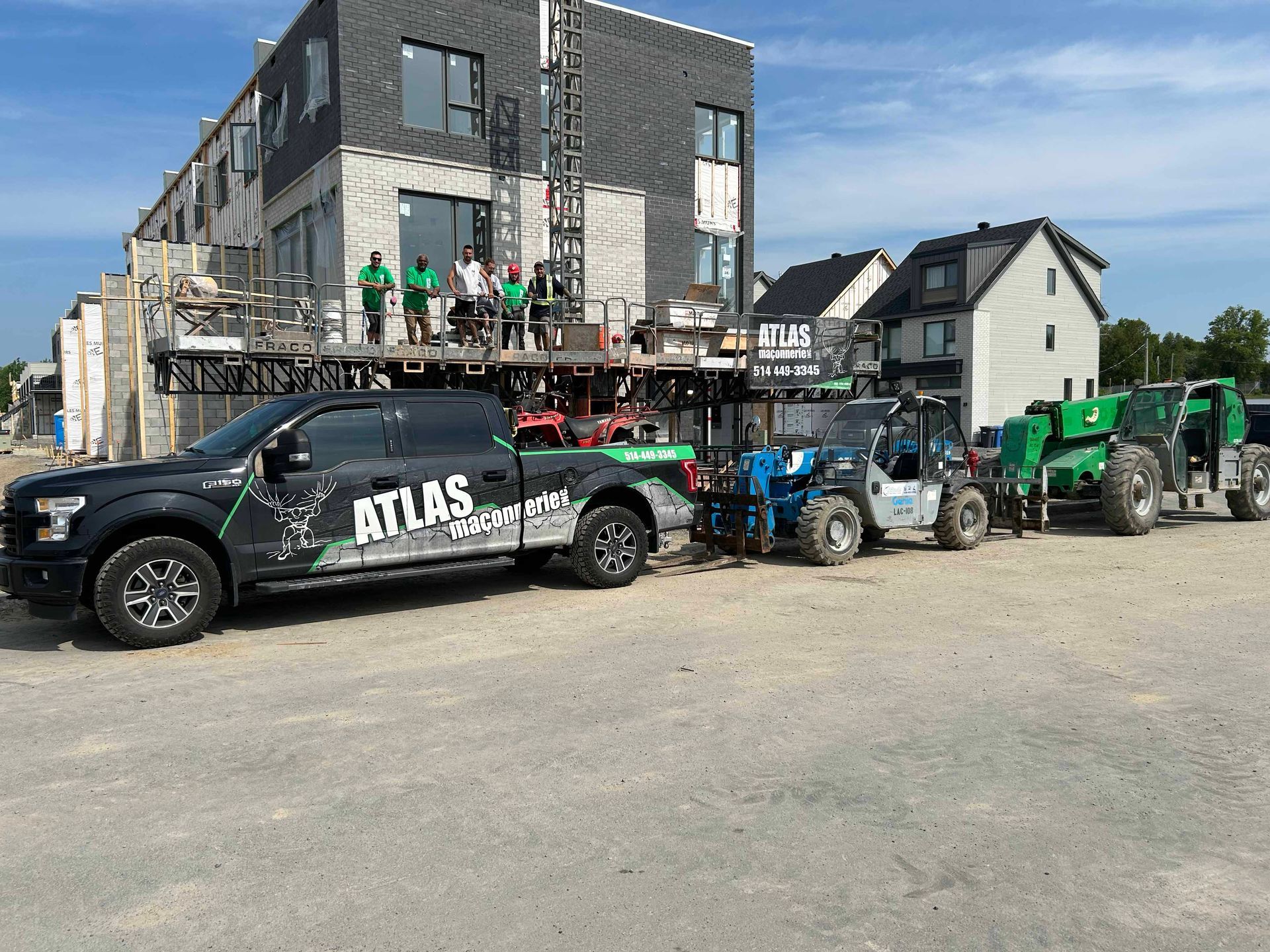 Un camion atlas noir est garé devant un bâtiment en construction.