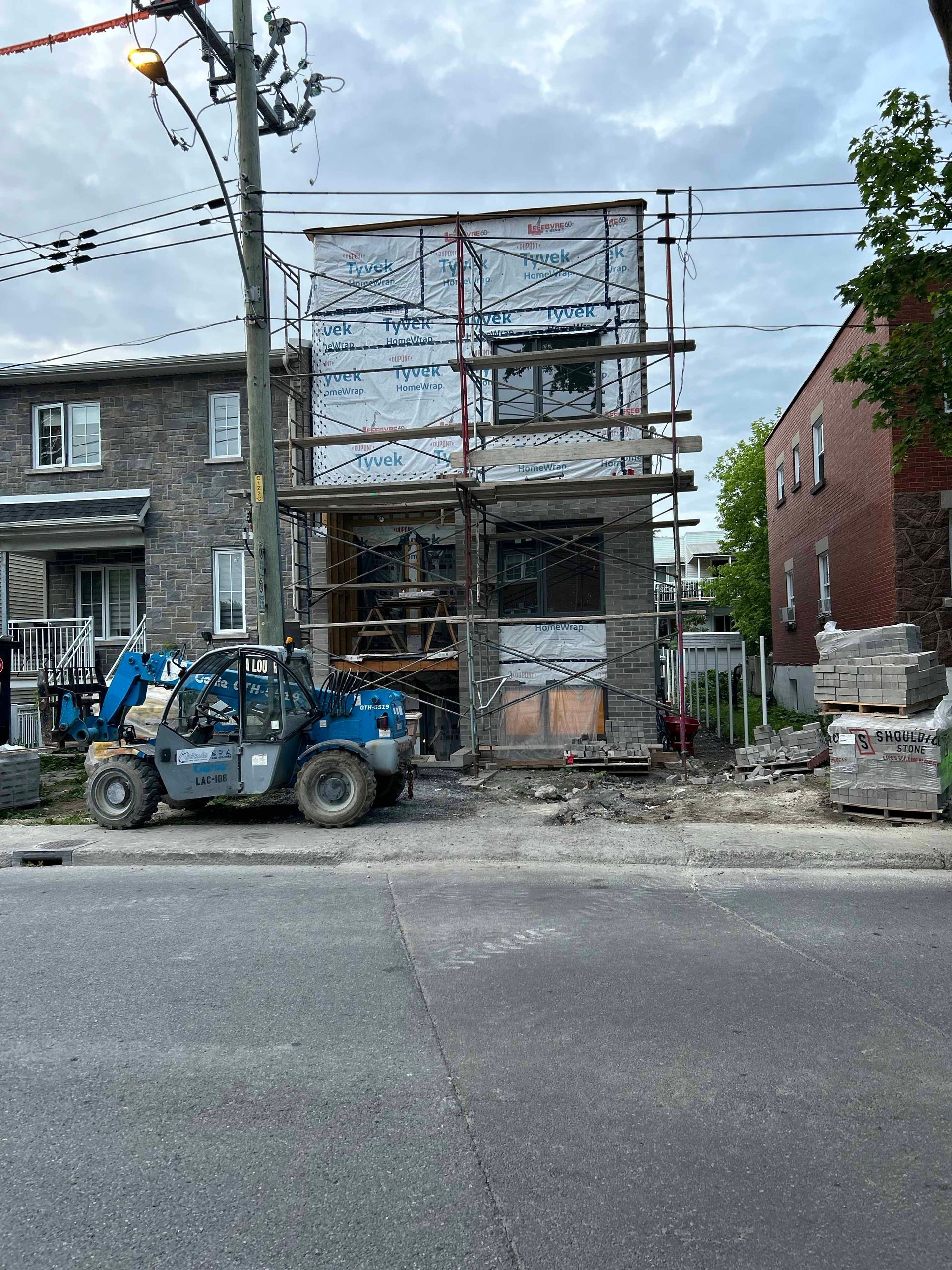 Un chariot élévateur est garé devant un bâtiment en construction.