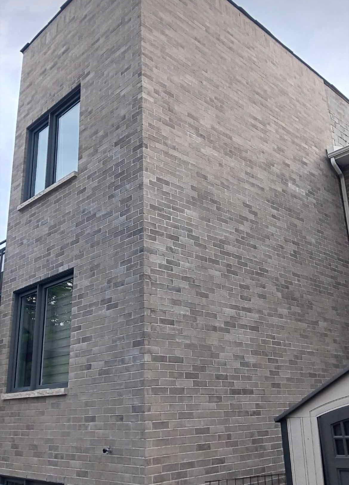 Un bâtiment en briques avec beaucoup de fenêtres et un hangar devant.