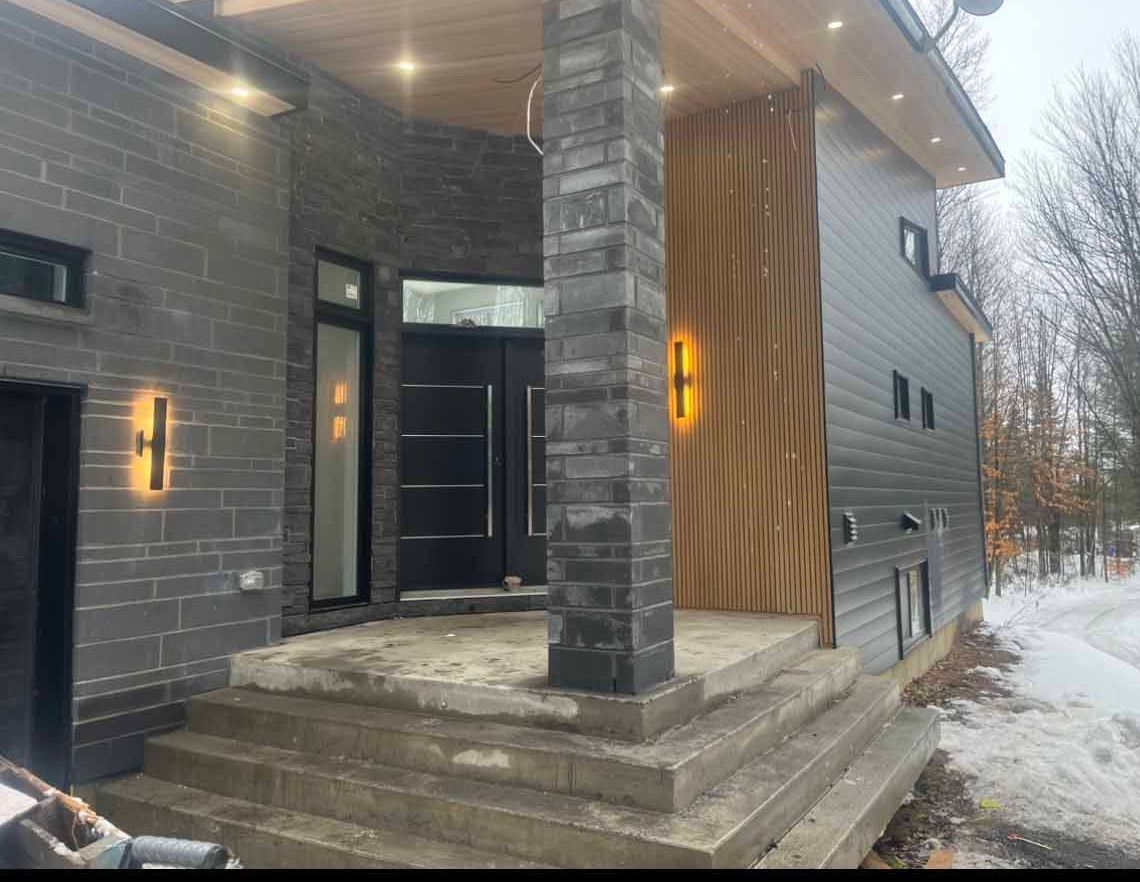 Une grande maison avec un porche et des escaliers dans la neige.