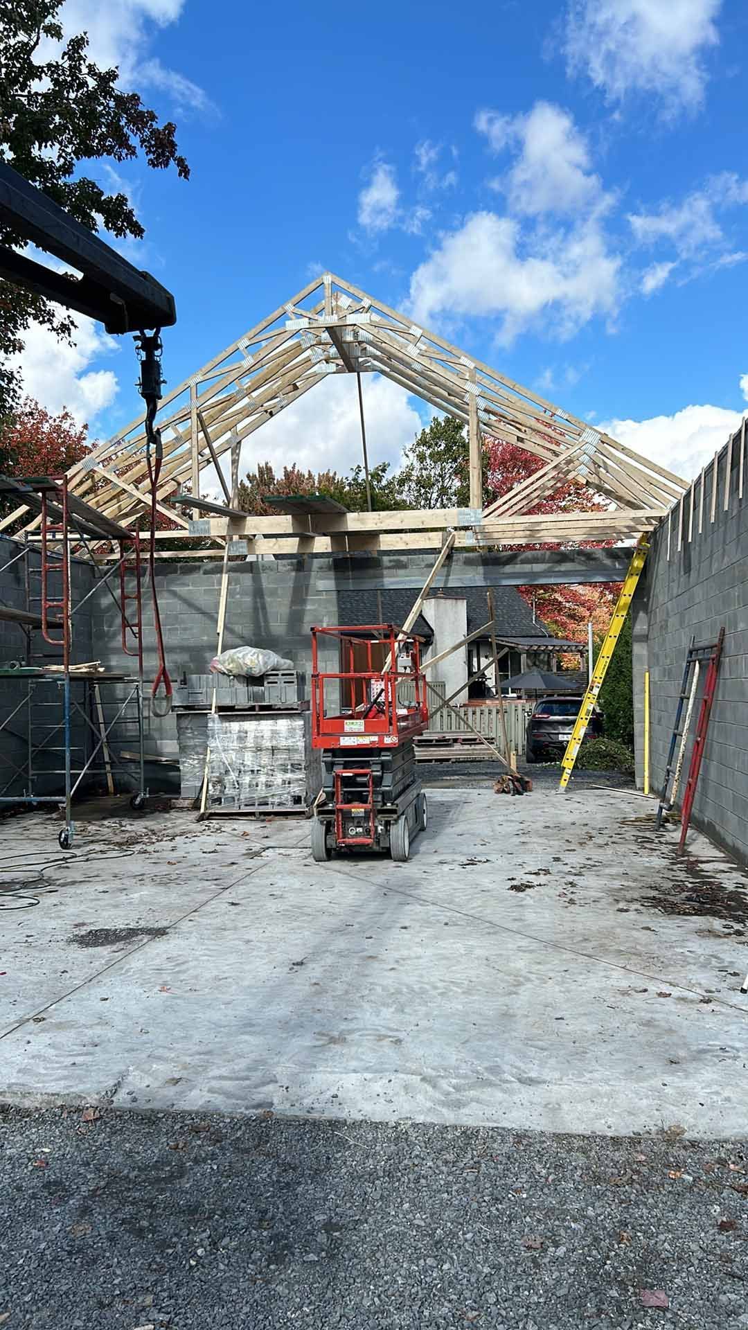 Un chantier avec une grue et un chariot élévateur devant un bâtiment en construction.