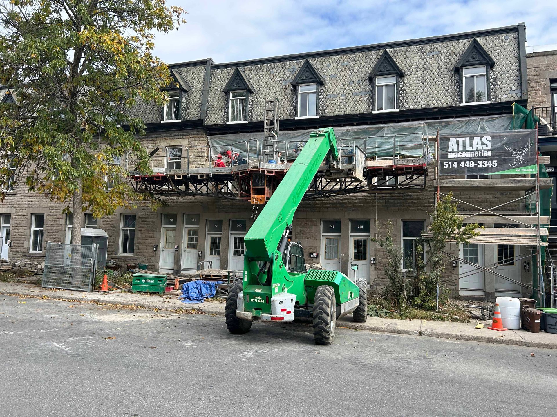 Un chariot élévateur vert est garé devant un bâtiment en construction.