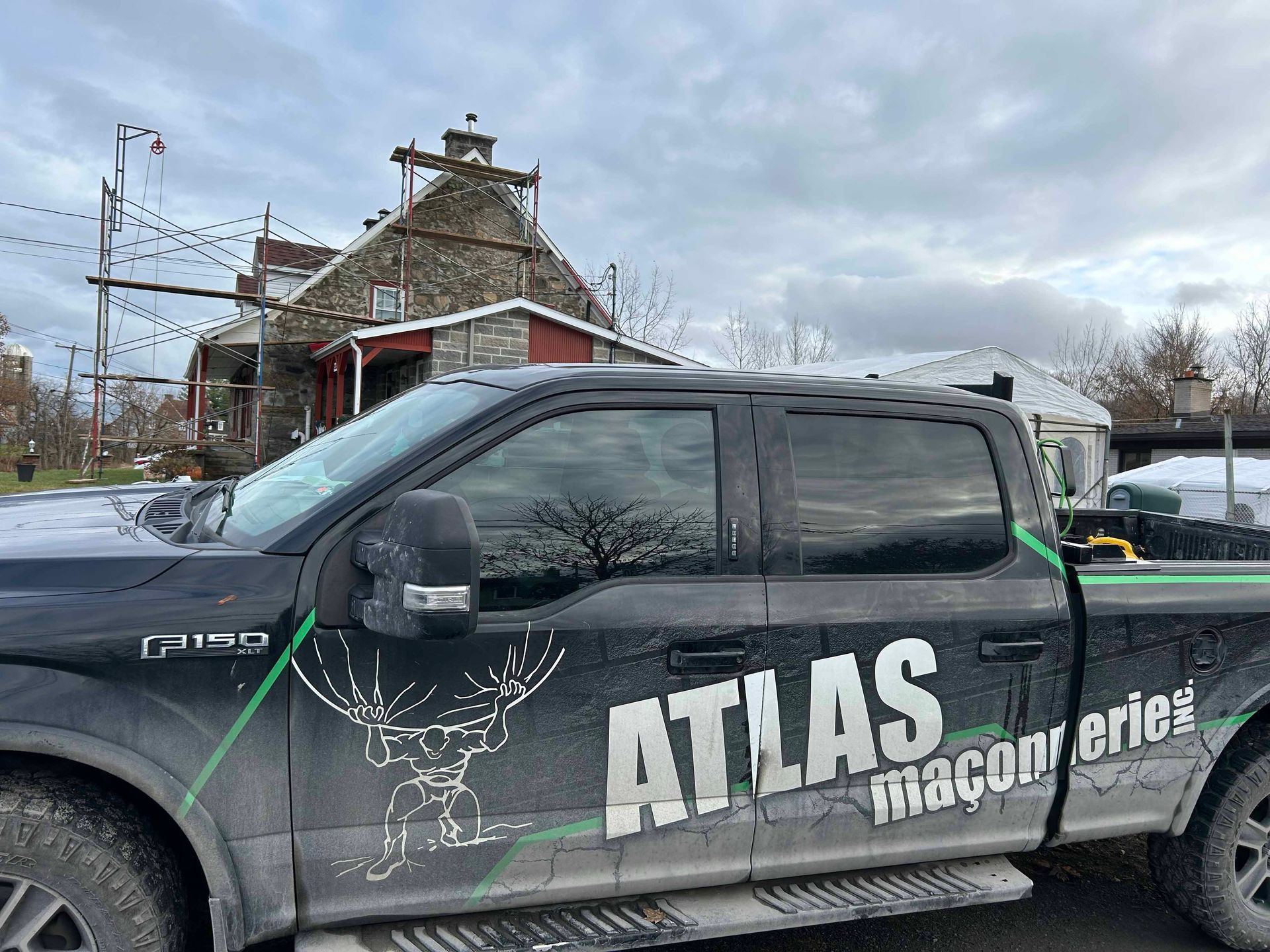 Un camion noir avec un cerf sur le côté est garé devant une maison.