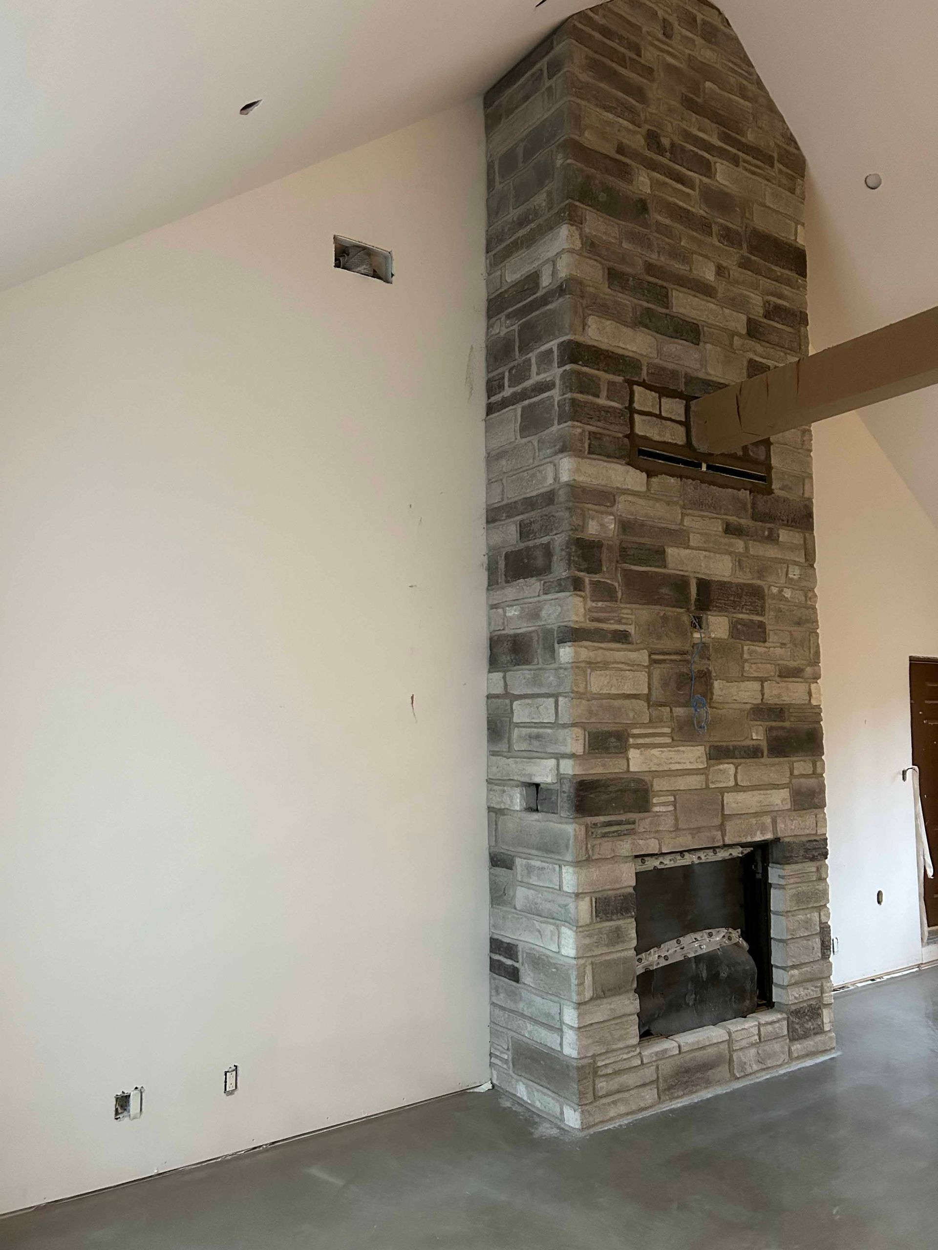 Il y a une grande cheminée en pierre au milieu de la pièce.