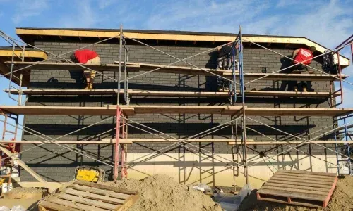 Un groupe d'ouvriers du bâtiment travaille sur le côté d'un bâtiment.