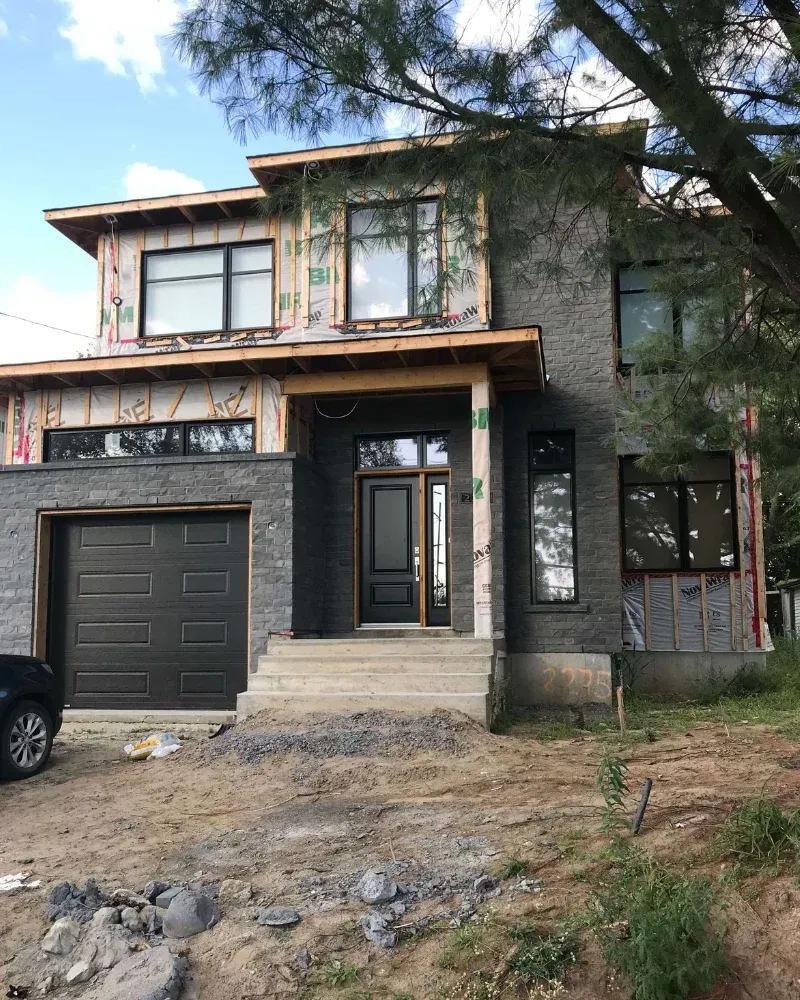 Une maison en construction avec une voiture noire garée devant.