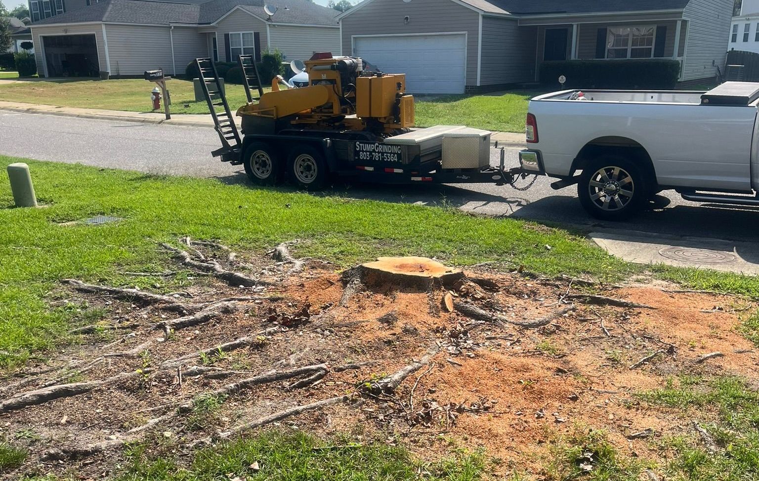 A tractor is cutting down a tree in a yard.