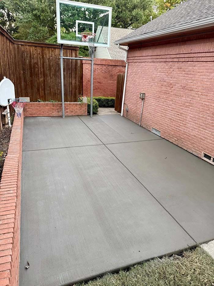 A man is working on a concrete patio in front of a house.
