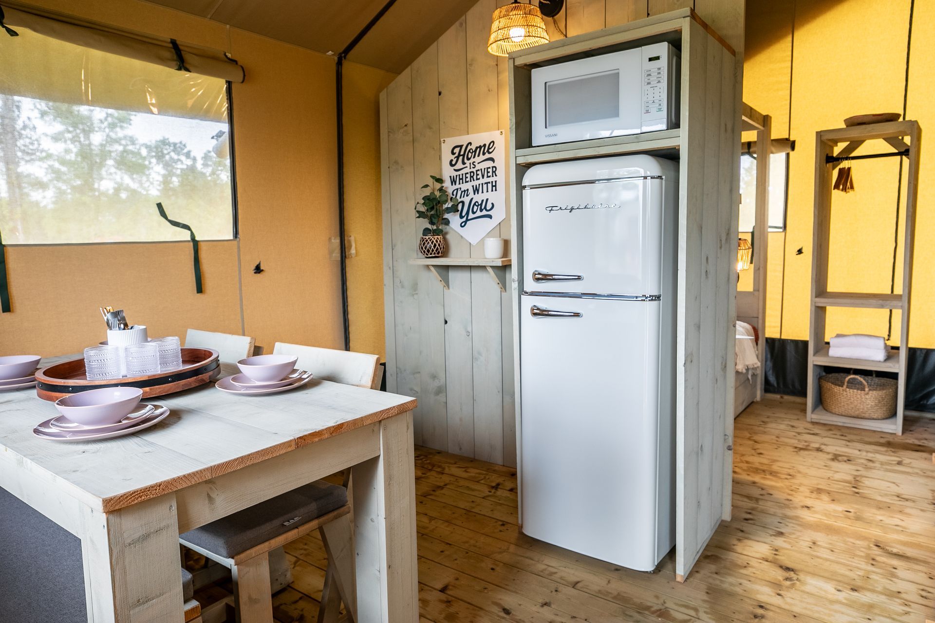 Interior photo of Canvas Cabin at Clay Cosmos glamping resort featuring refrigerator/freezer combo and dining area