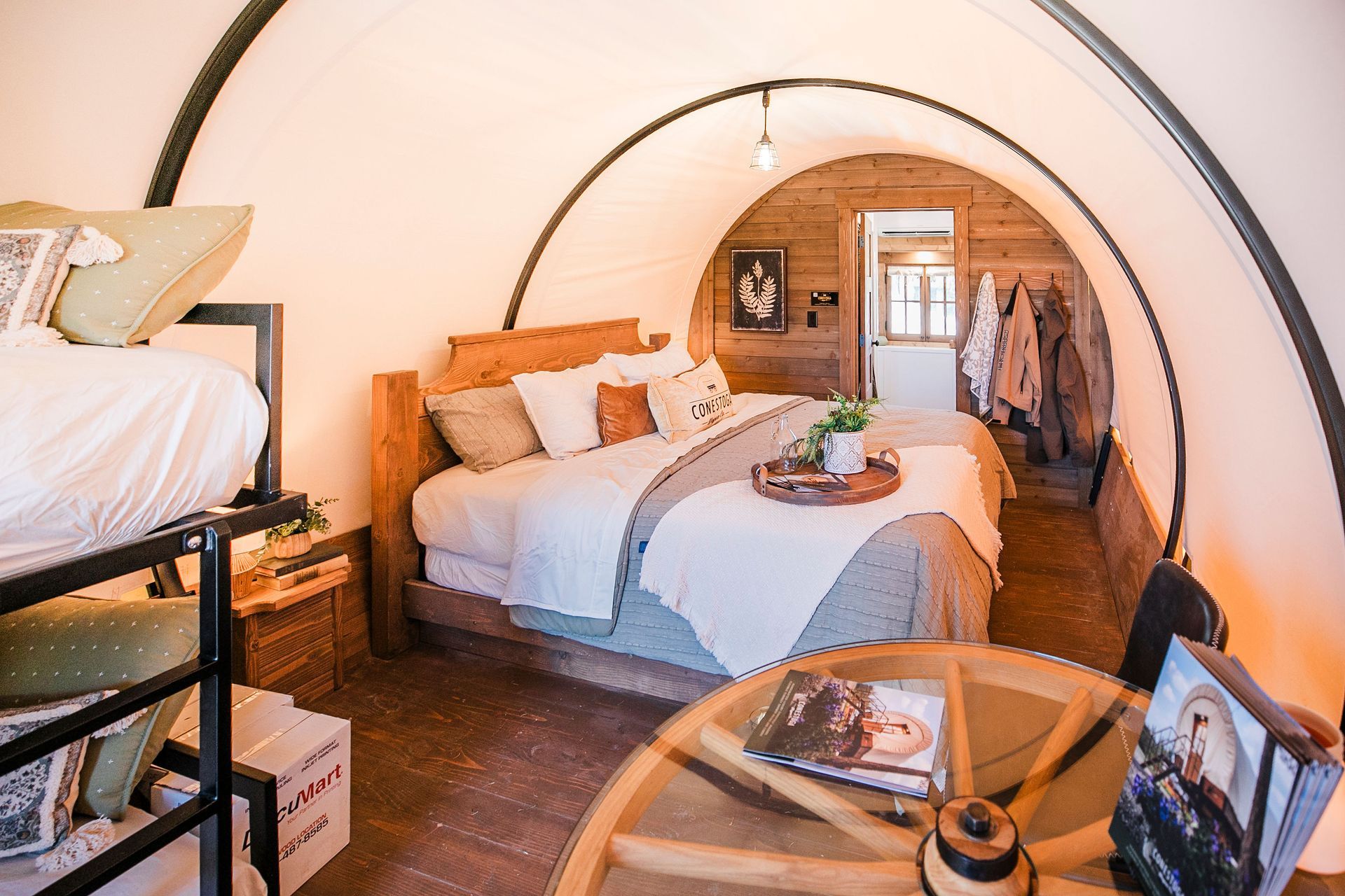 A cozy, wood-paneled bedroom with a large bed, light blue quilt, decorative pillows, and a flower arrangement on a tray.