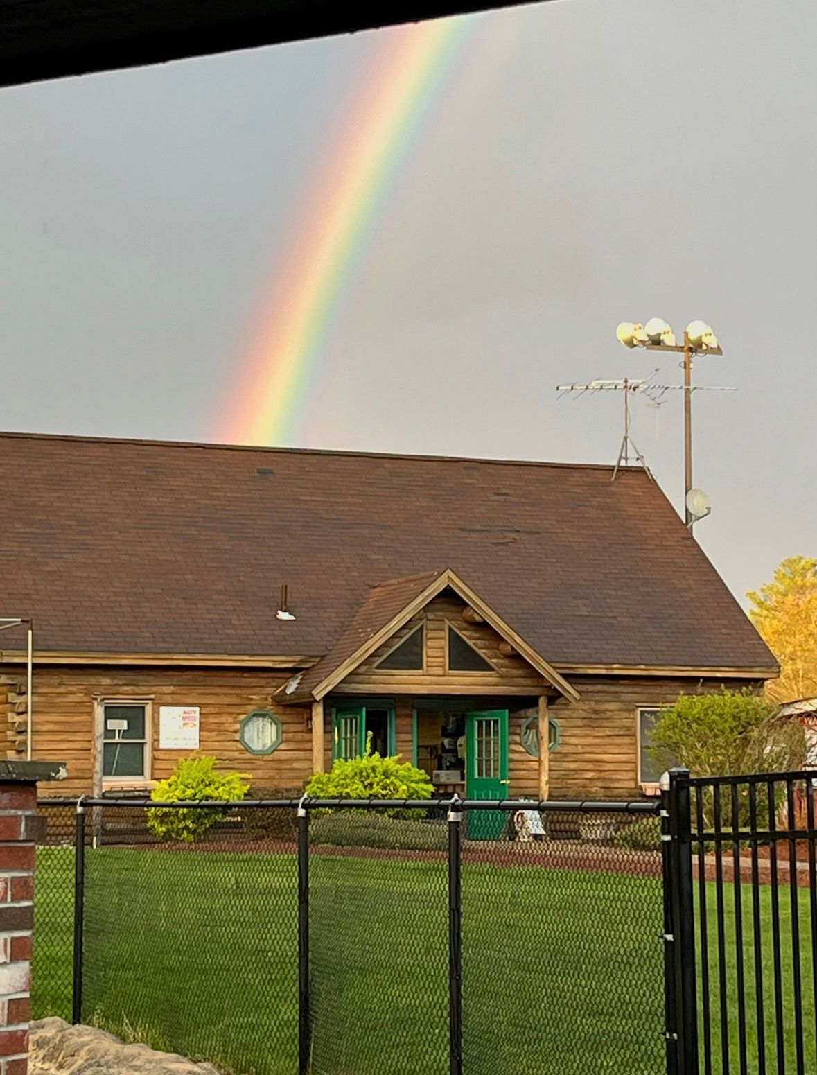 Rainbow over a wooden building with a green door.