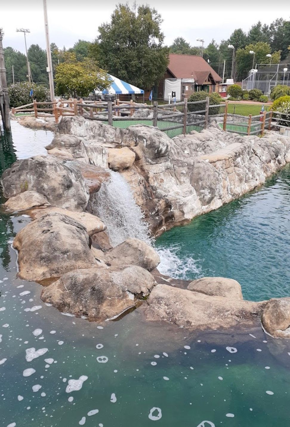 Miniature golf course with a waterfall feature and small pond.