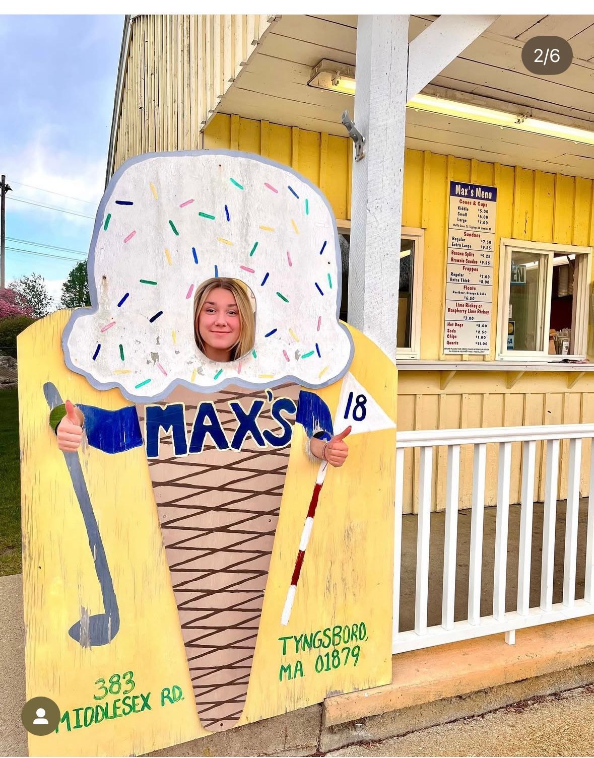 Woman in ice cream cone cutout outside Max's ice cream stand; yellow building and sign.