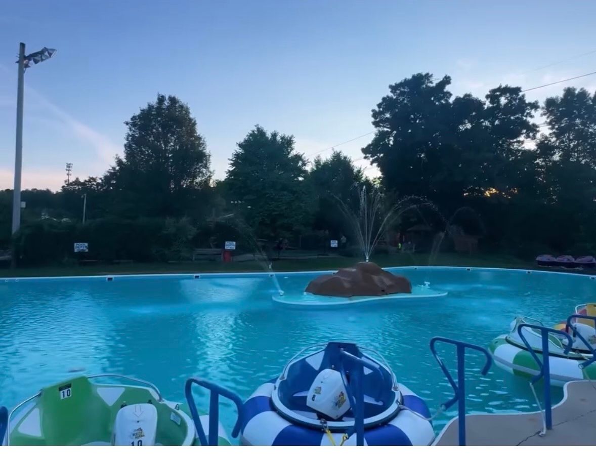 A pool with a fountain and paddle boats, under a partly cloudy sky.