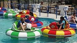 Water bumper boats in a pool, colorful with people inside.