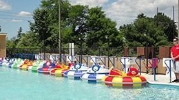 Colorful bumper boats in a pool, lined up with an attendant.