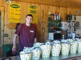 Man behind counter at golf driving range, selling buckets of golf balls.