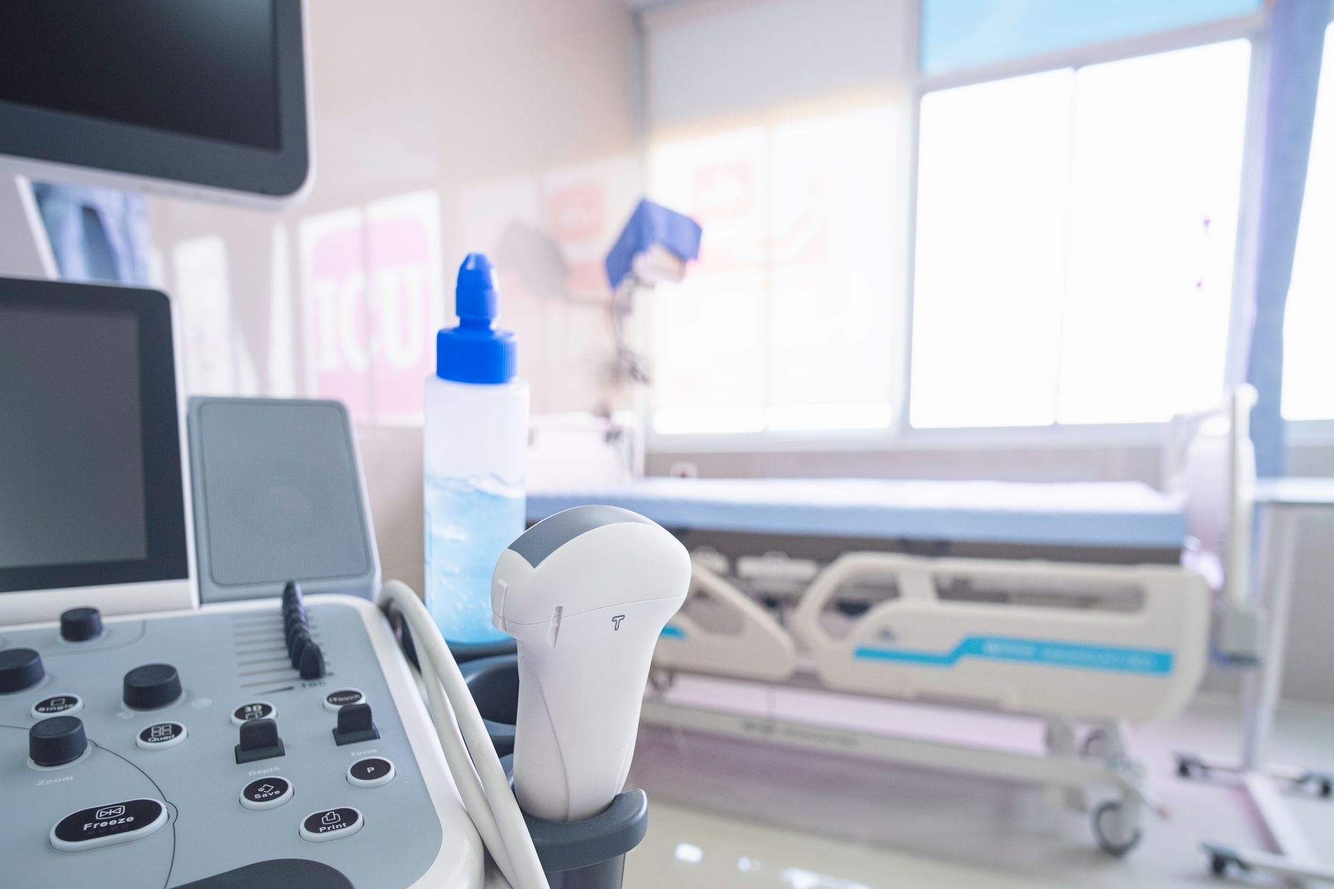 An ultrasound machine is sitting in a hospital room next to a hospital bed.